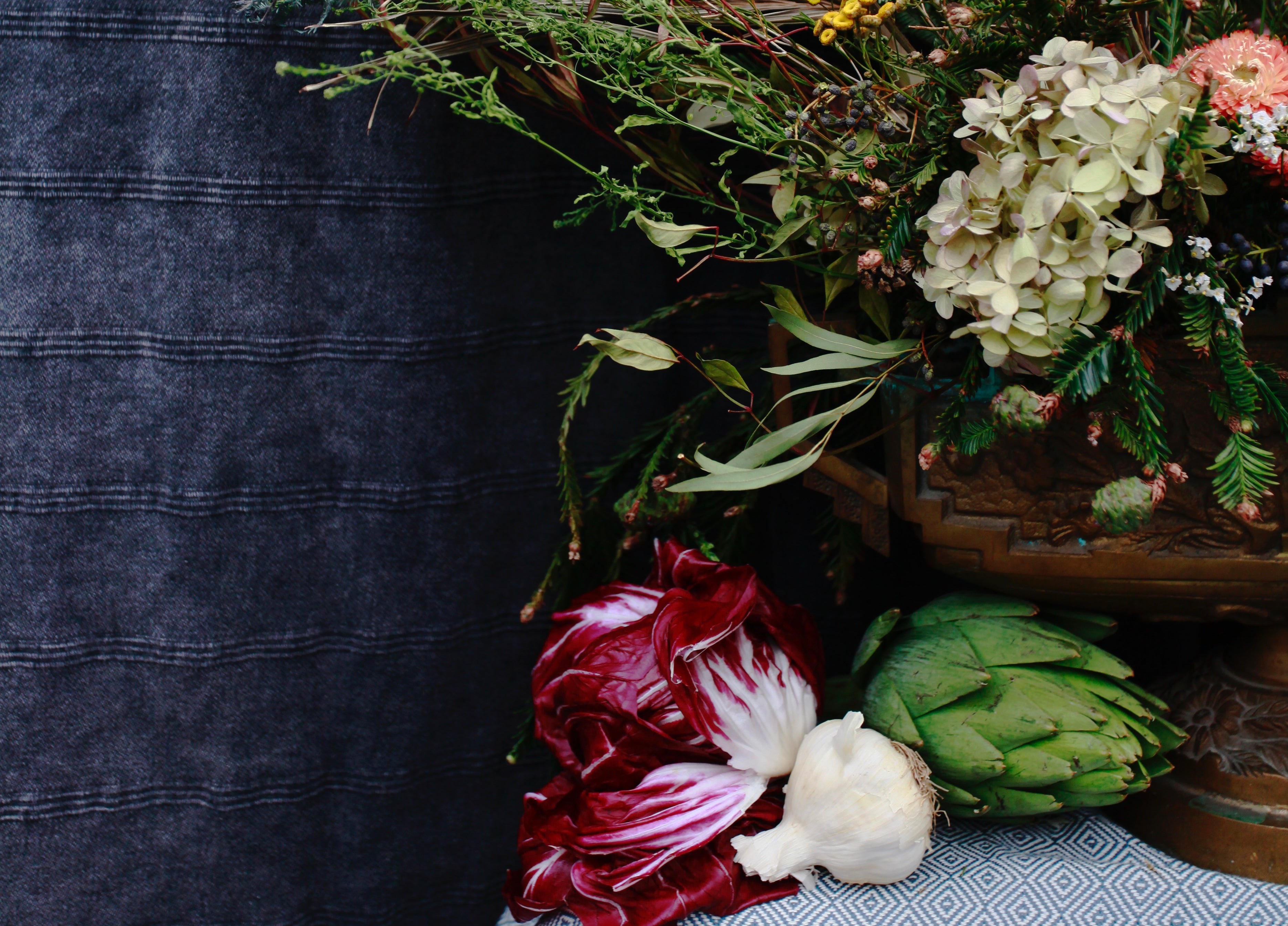fall veggies in front of a floral urn with a denim backdrop.