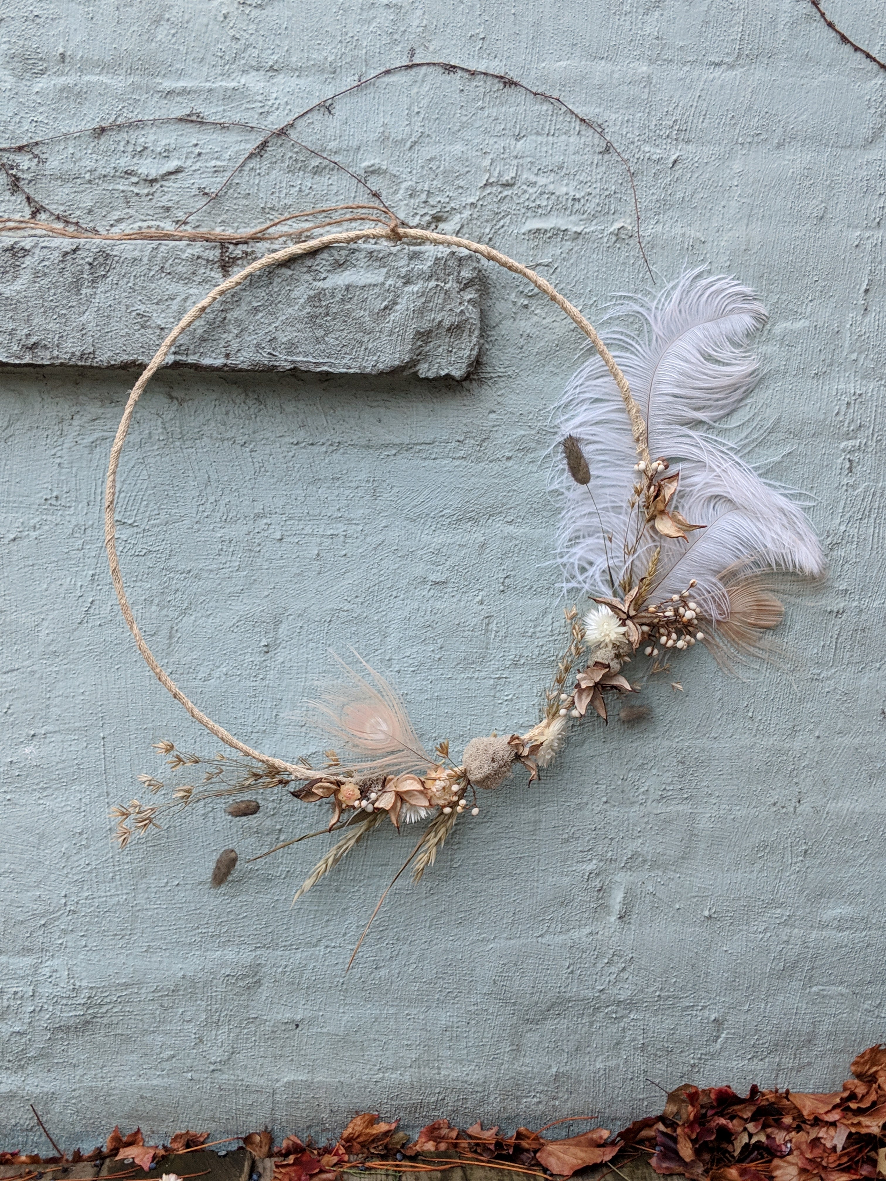 Dreid floral minimalist wreath against a light blue wall created by Sprout Home. www.sprouthome.com.
