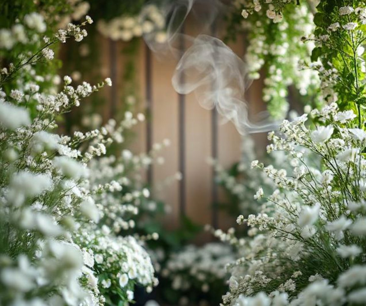 White flowers surrounding the viewer with incense smoke wafting in the background. Calm and serene