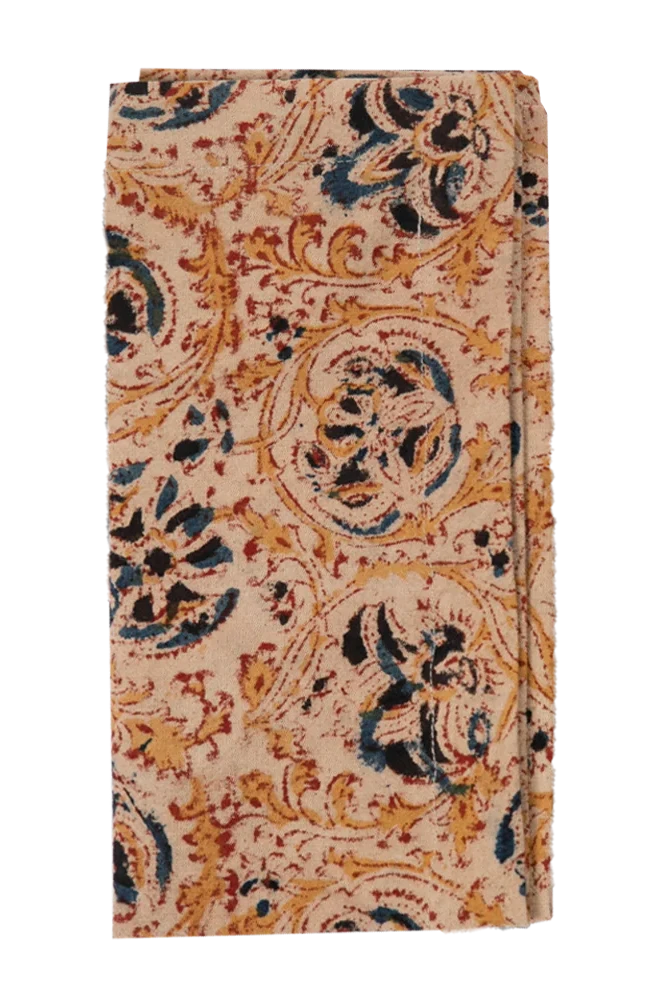 A folded cloth napkin with a floral and paisley pattern in beige, brown, and blue colors. ©Filling Spaces