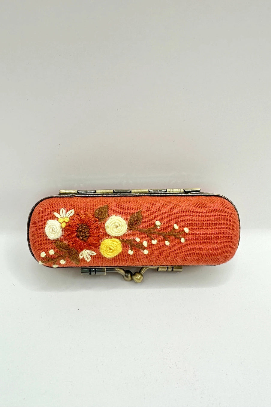Decorative orange box with floral embroidery on a white background ©Quince Fables
