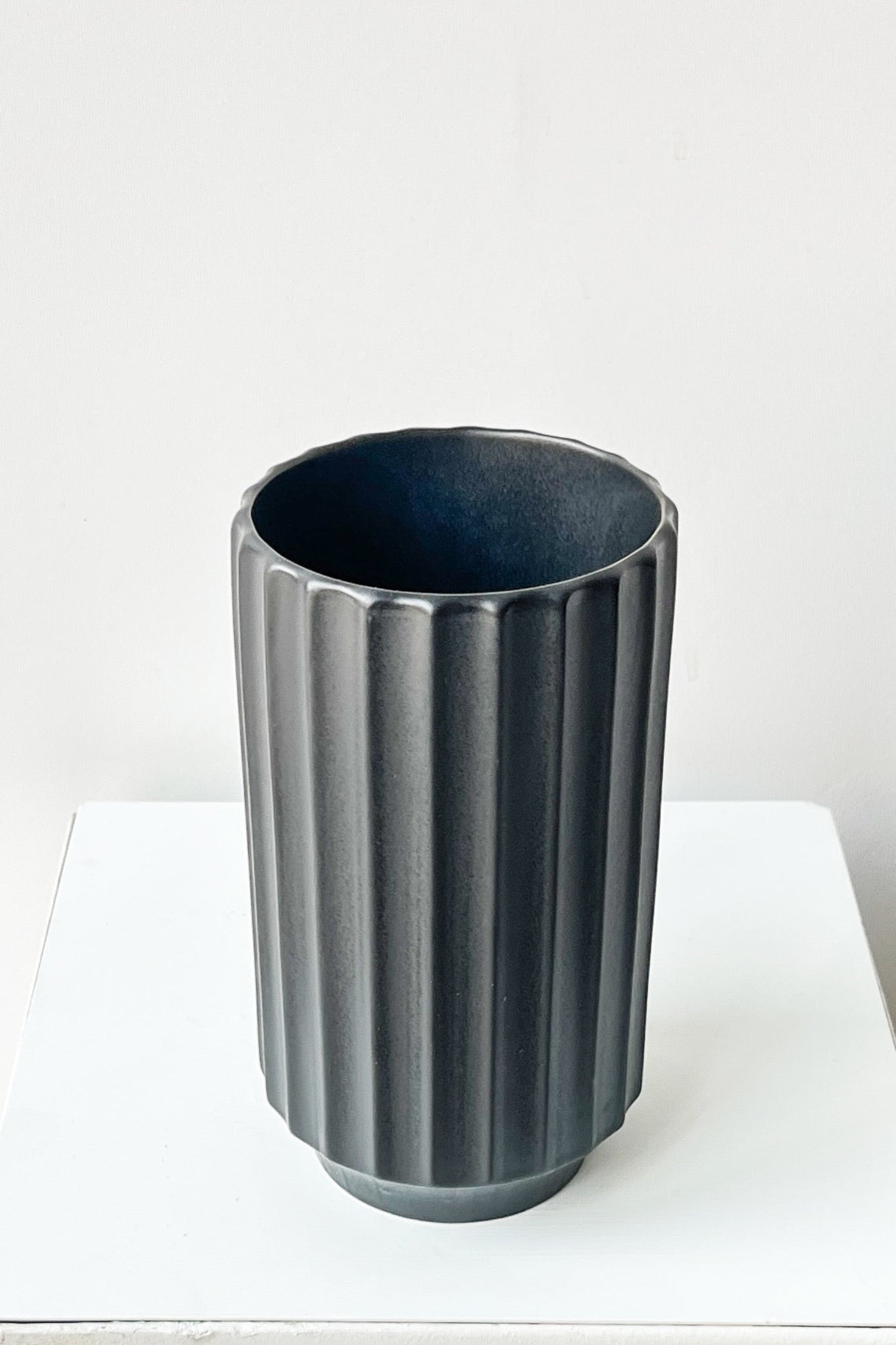 Black ribbed vase on a white surface with a white background ©Sprout Home