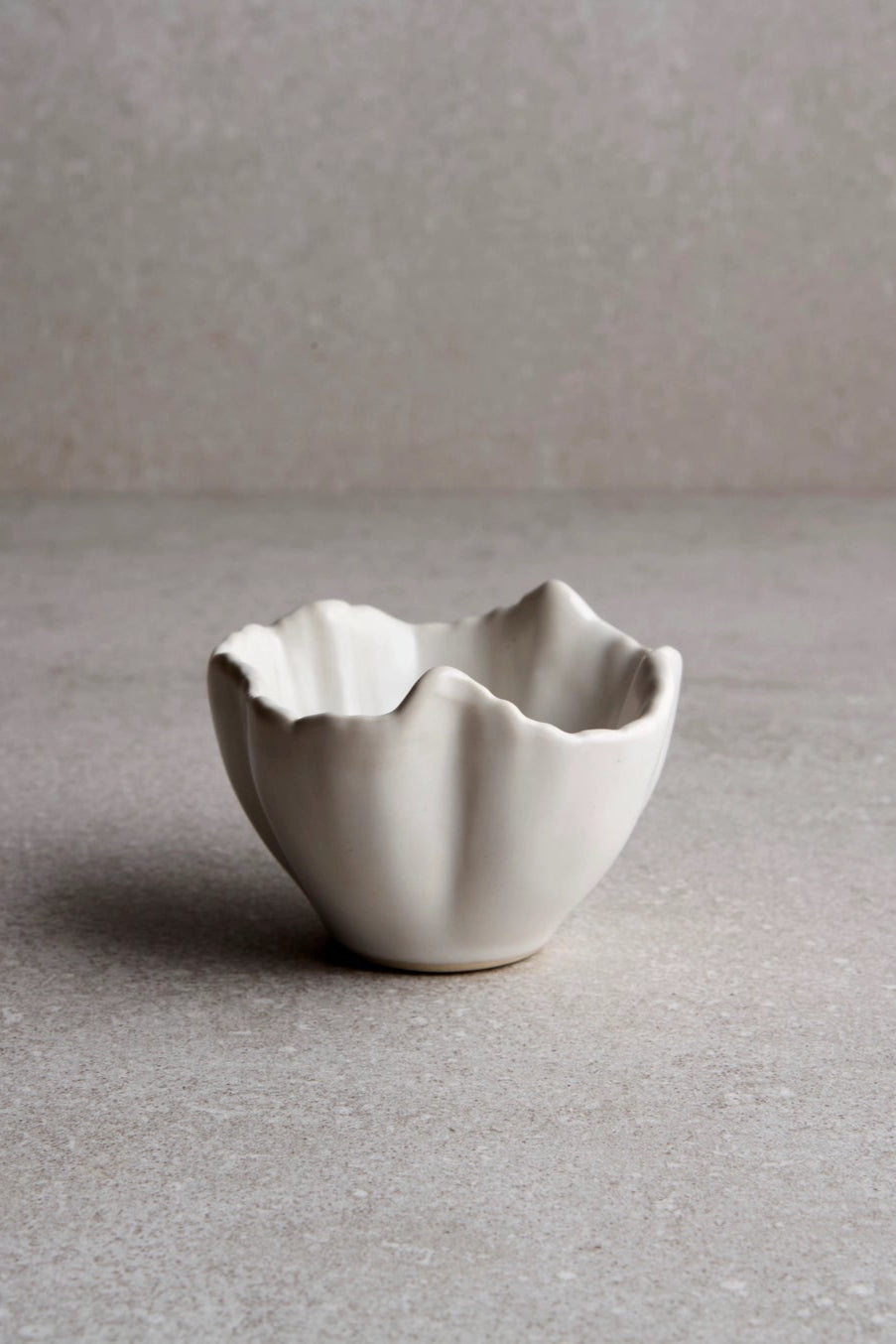 Small ceramic Petal bowl on a gray surface with a neutral background ©Goodies