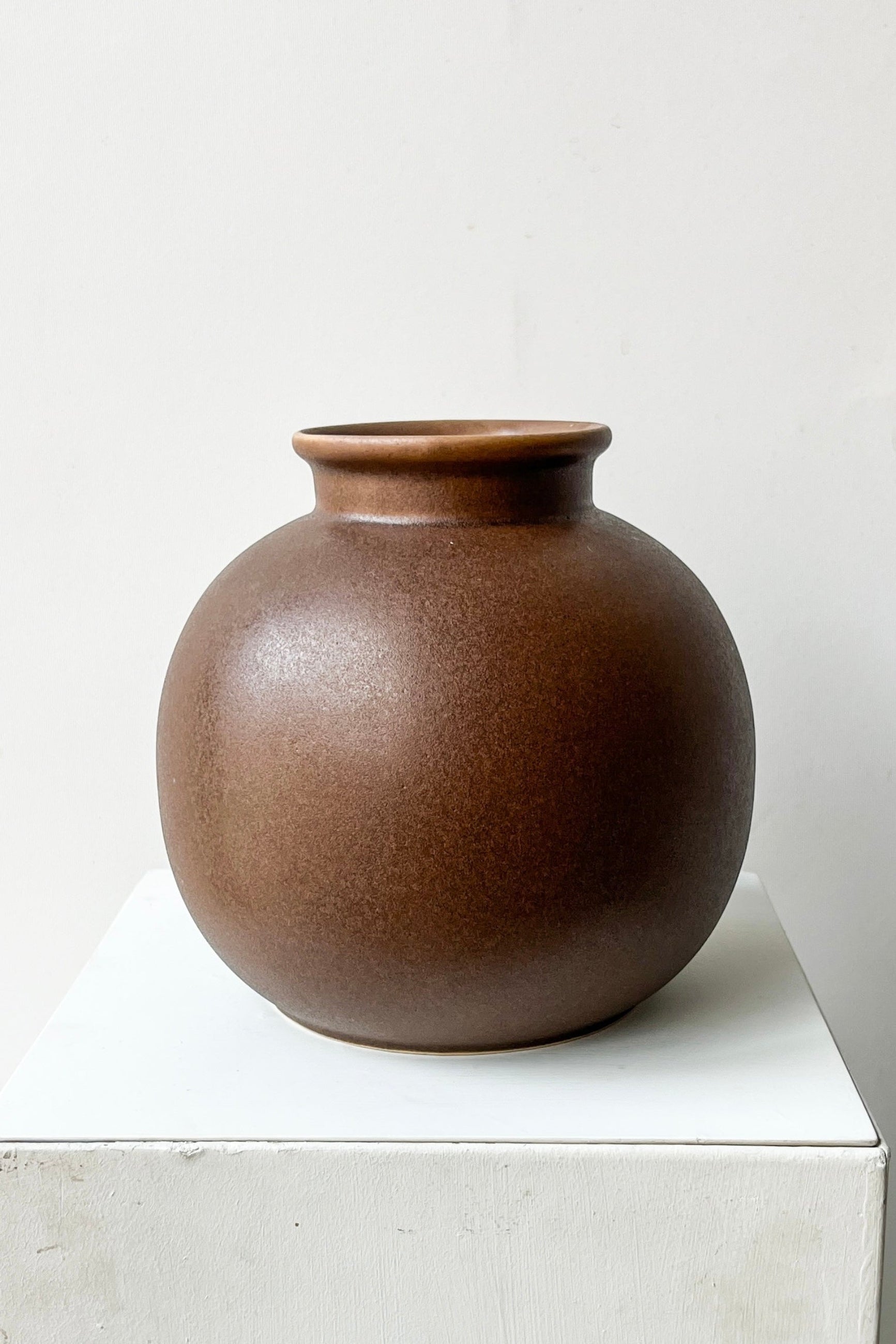 Brown ceramic vase on a white surface with a light gray background ©Sprout Home