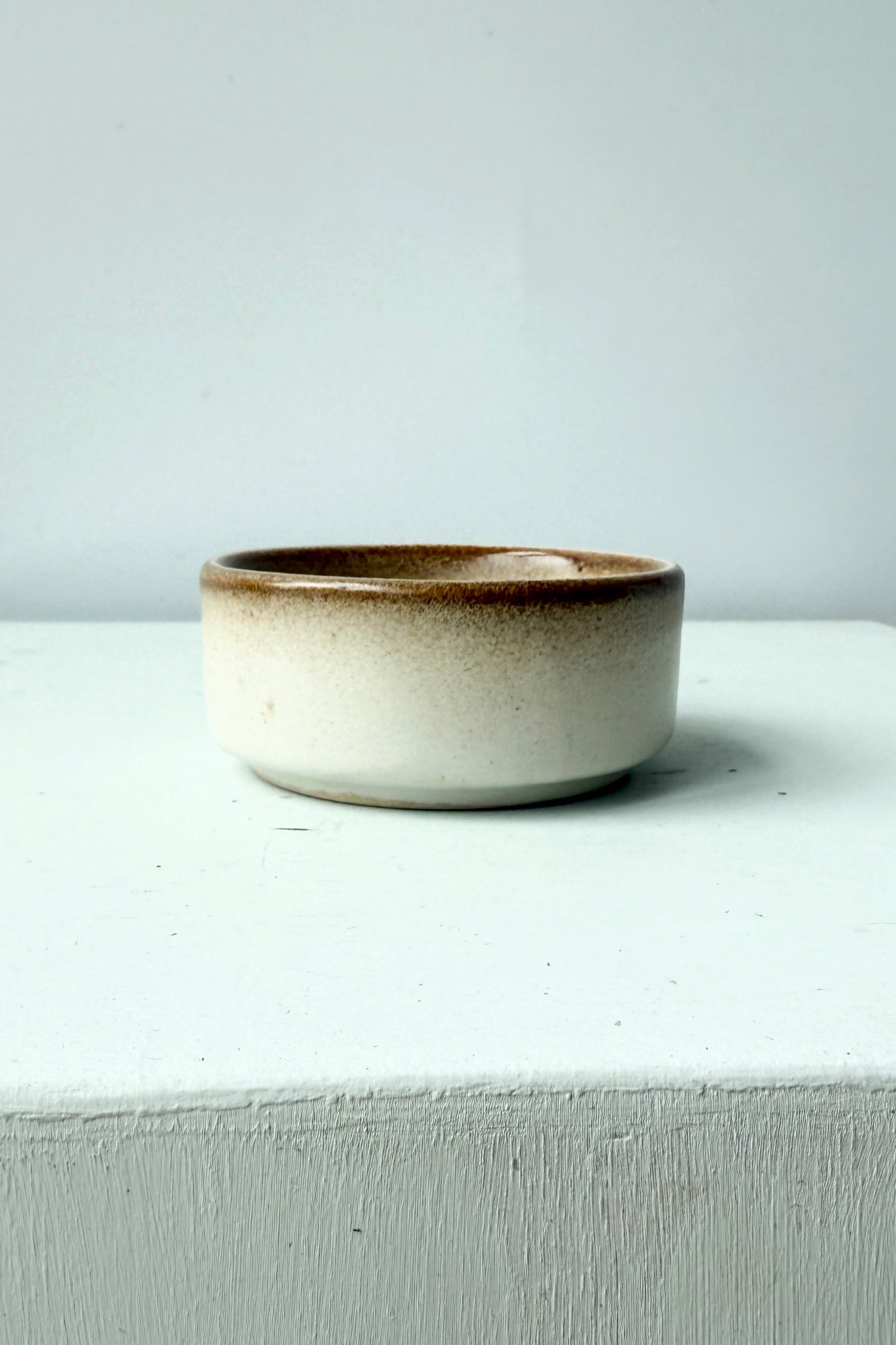 Ceramic bowl with brown rim on a white surface ©Sprout Home