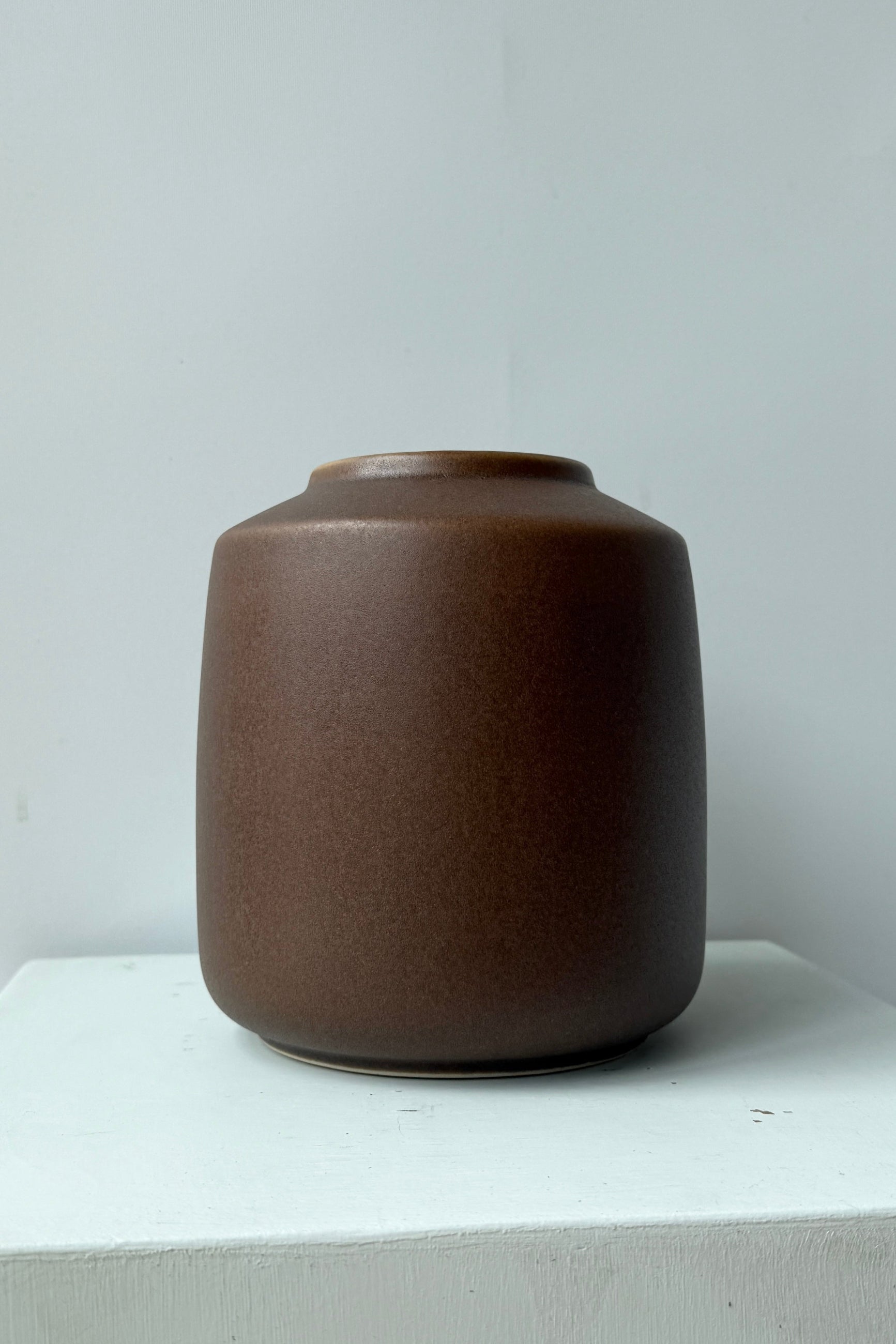 Brown ceramic vase on a white surface with a light gray background ©Sprout Home