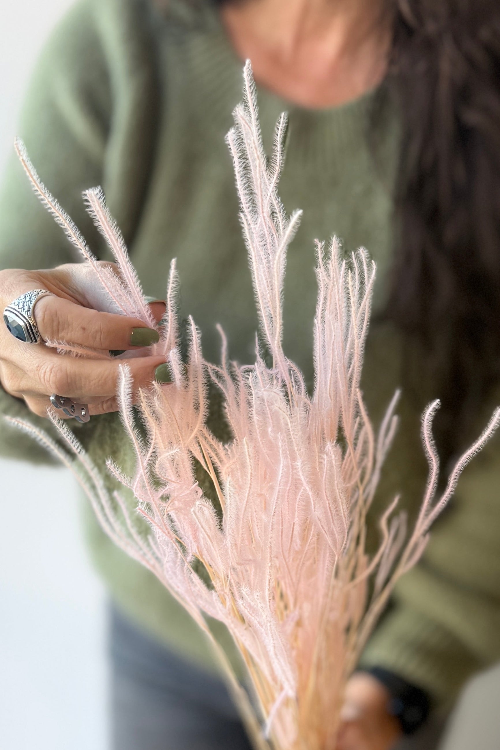 Person holding a bouquet of dried and preserved blush colored Ouro with a blurred background ©Sprout Home