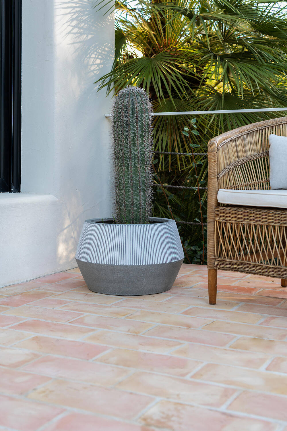 Harley Low Pot white stripe by Pottery Pots planted with a cactus and sitting on a porch by a wicker chair