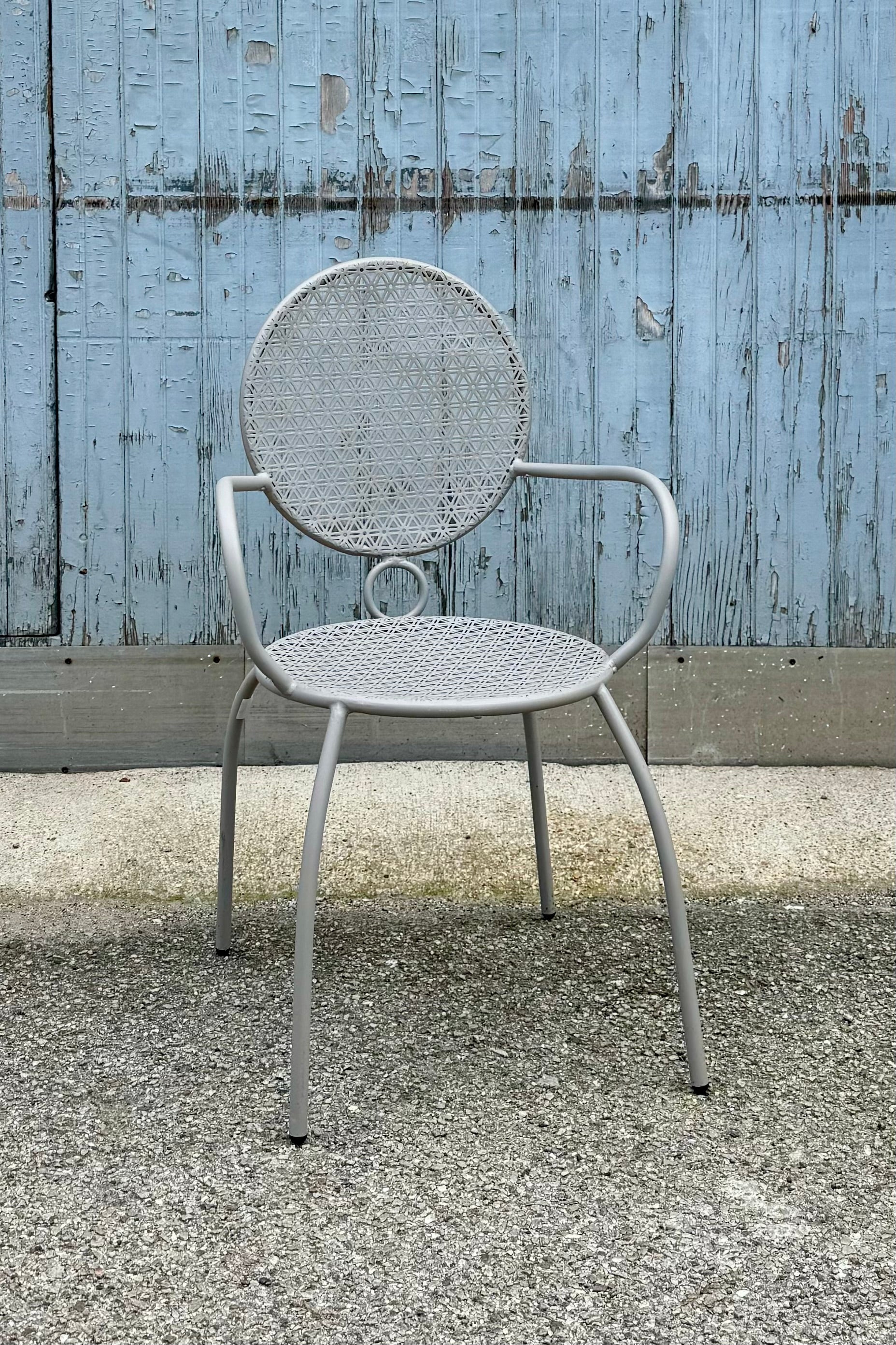 The gray bistro chair at sprout home against a blue gray wood wall.