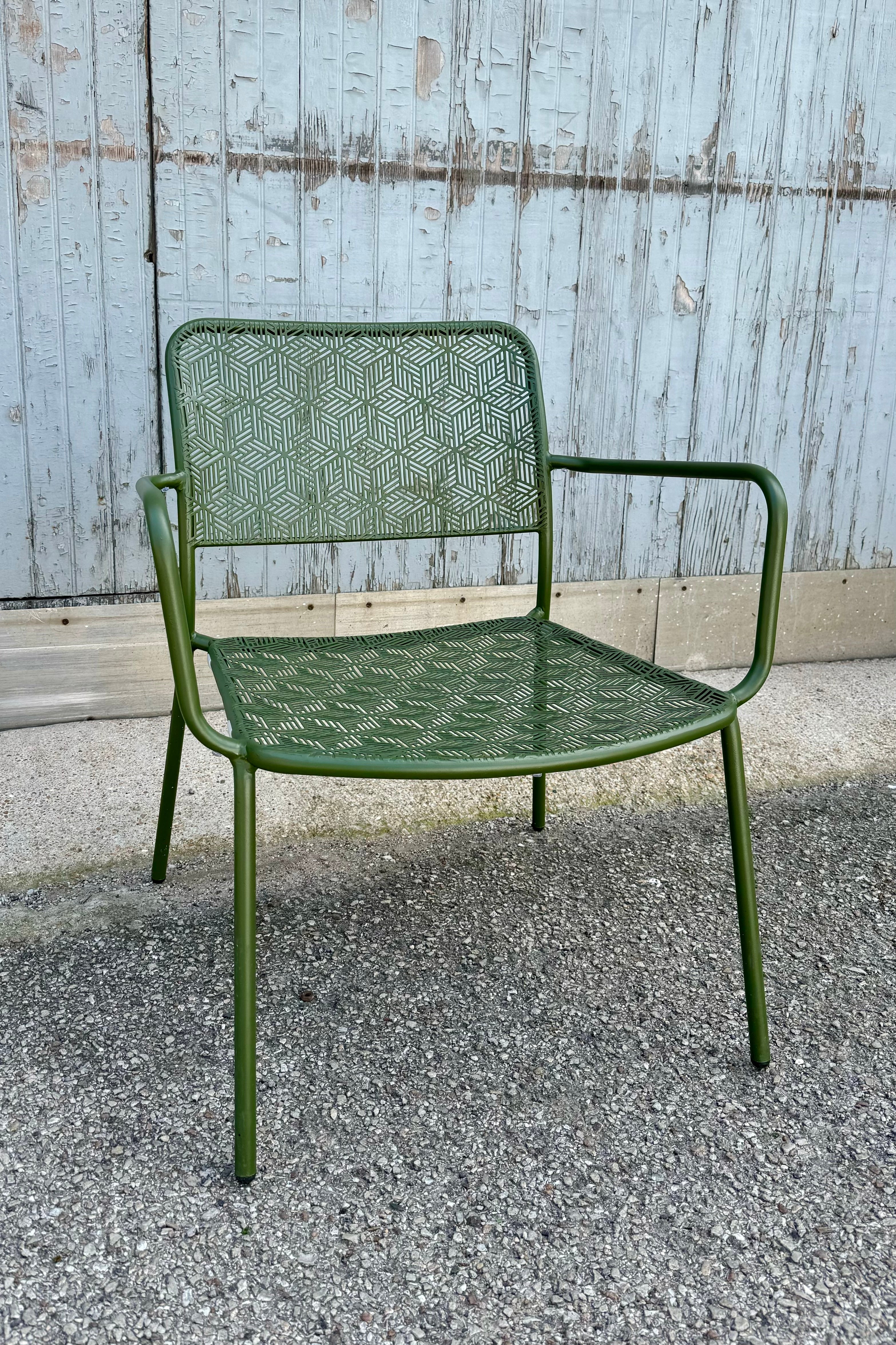 The green low profile martini chair in front of a wood gray wall.