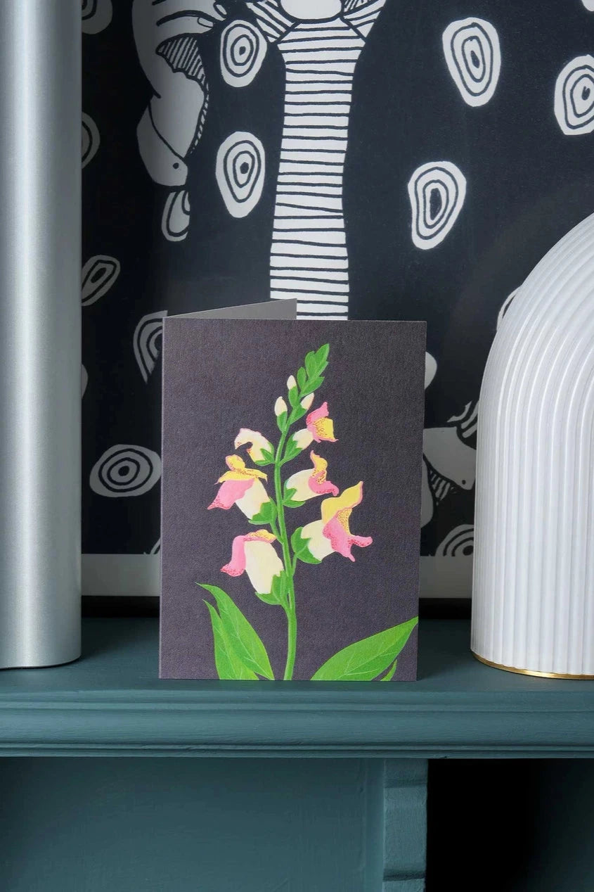 Snapdragon card by Stengun Drawings on a shelf sitting upright with a graphic wallpaper behind it.