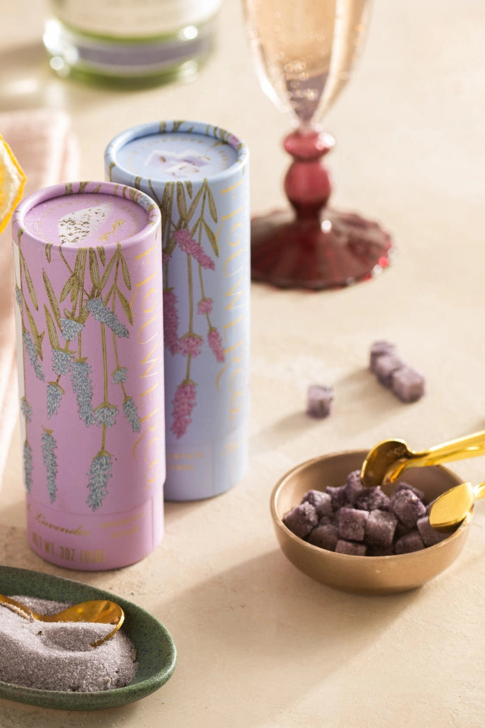 Two cans of lavender-flavored cubes with a glass of lemonade and snacks on a table. ©Flouwer Co.