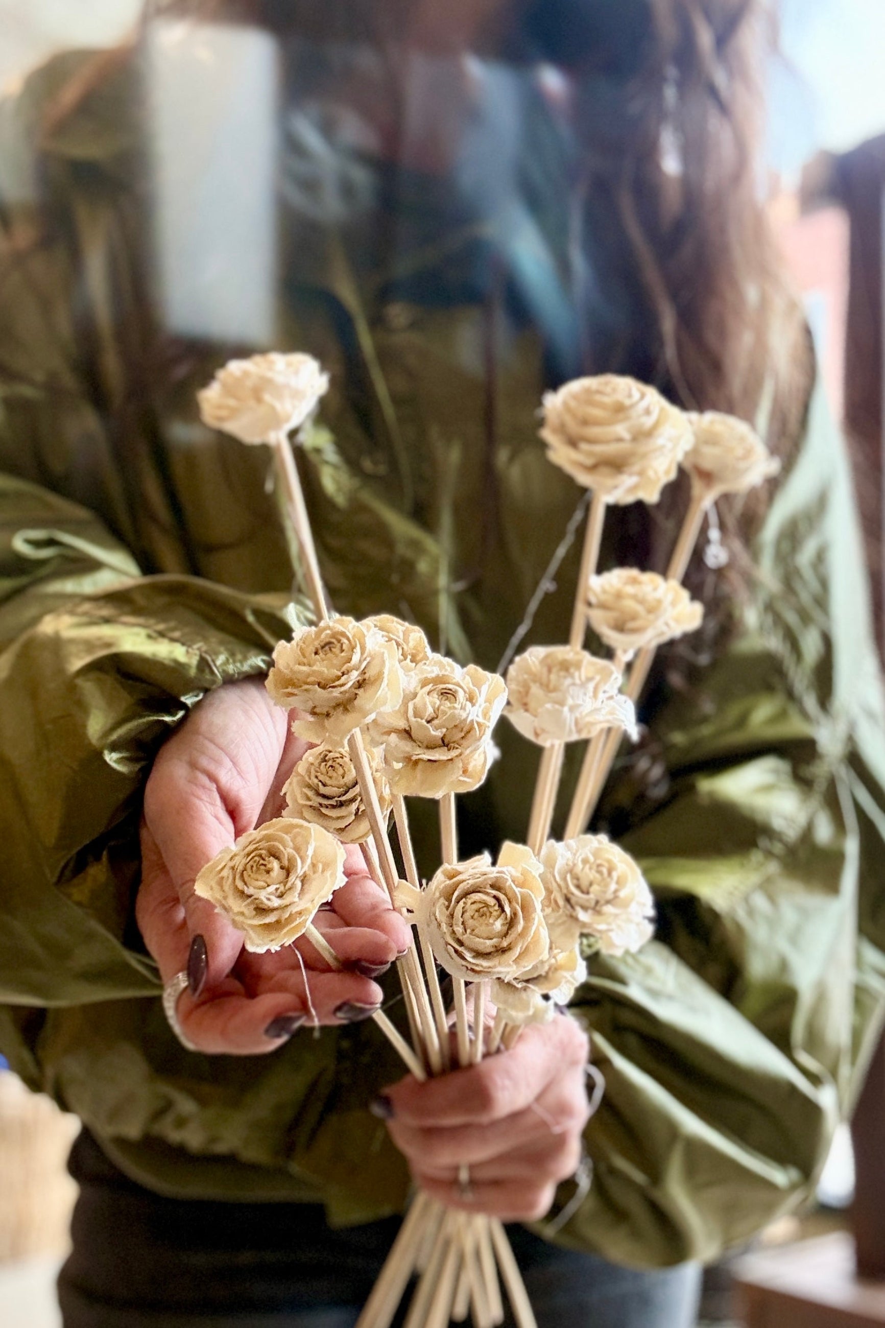 Person holding a Cedar Rose Bleached Pastel Preserved Bunch with a green jacket. ©Sprout Home