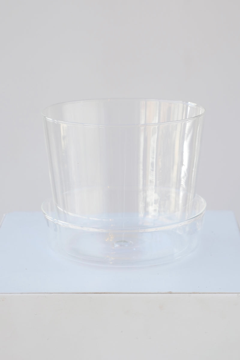 Glass pot and saucer shown from the top side blending in to the white background. 