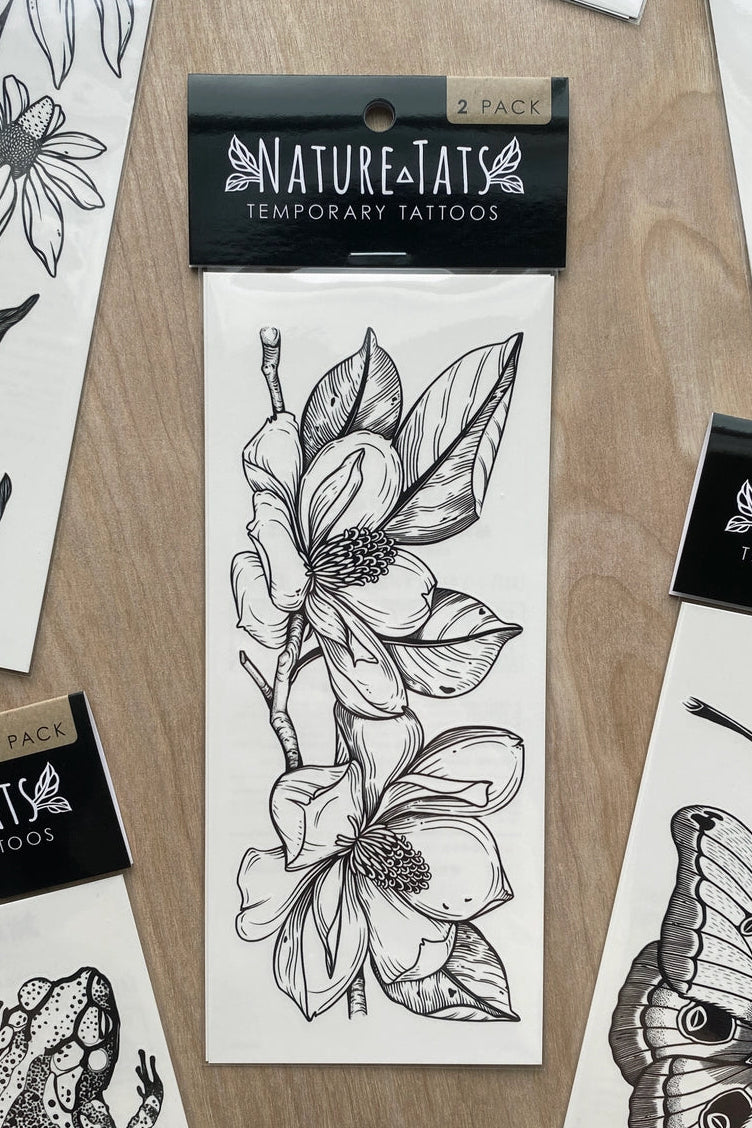 Nature temporary tattoos with a Magnolia Tattoo in the center on a wooden surface. ©Nature Tats
