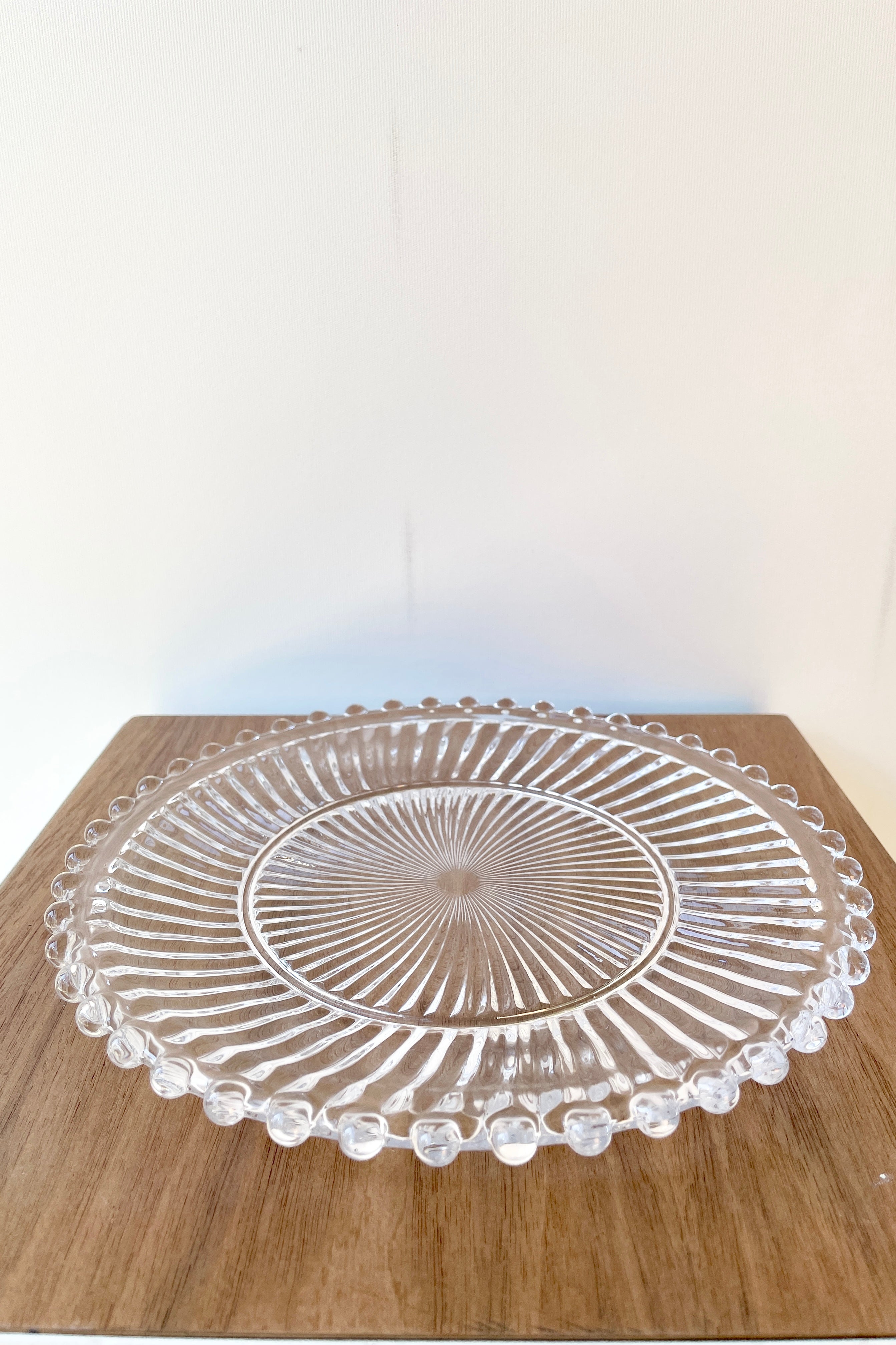 Dentelle clear aurora glass plate on a wood grain surface