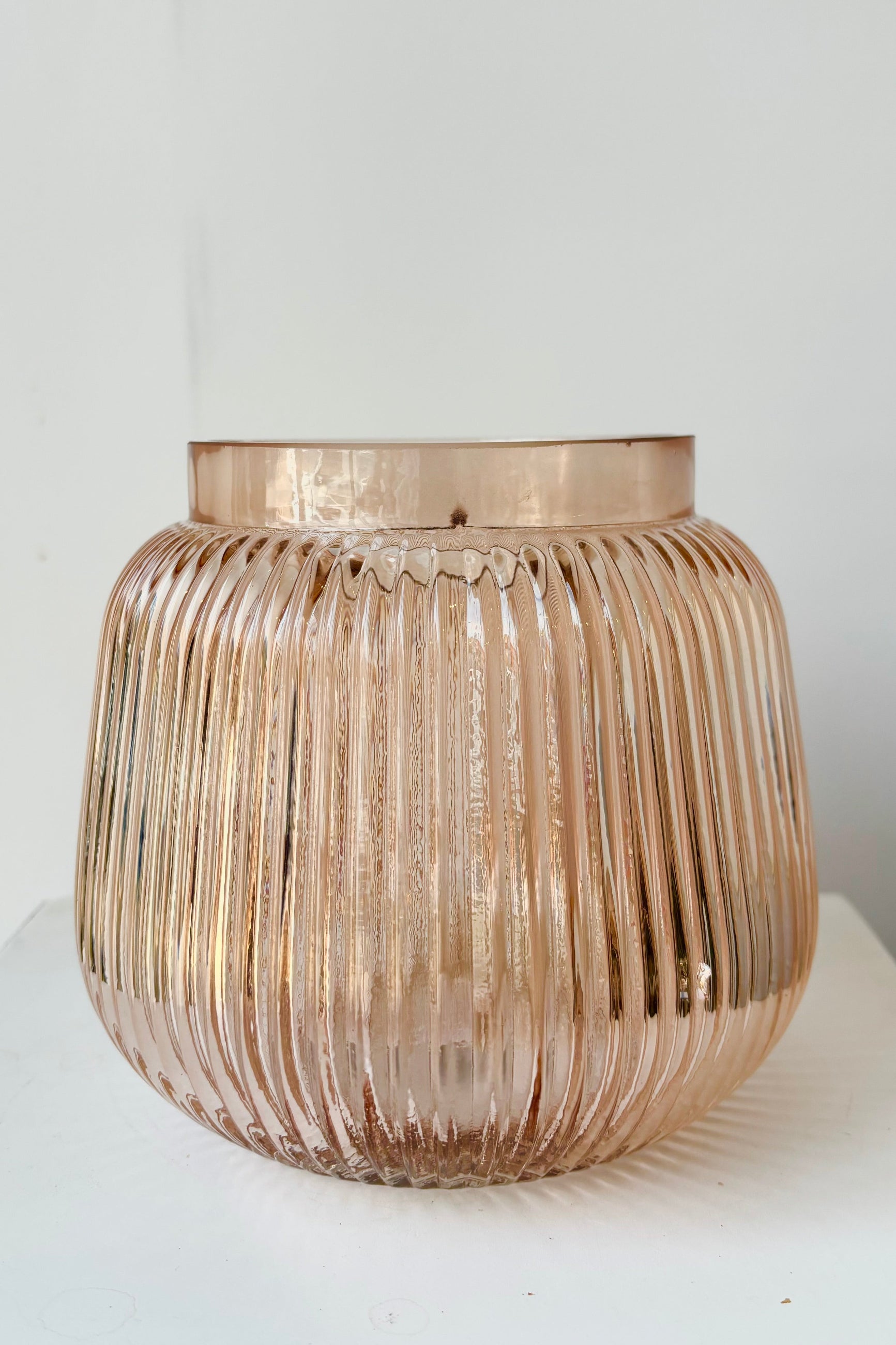 Rose color tinted, wide mouth glass vase with vertical ribbing against white background ©Sprout Home