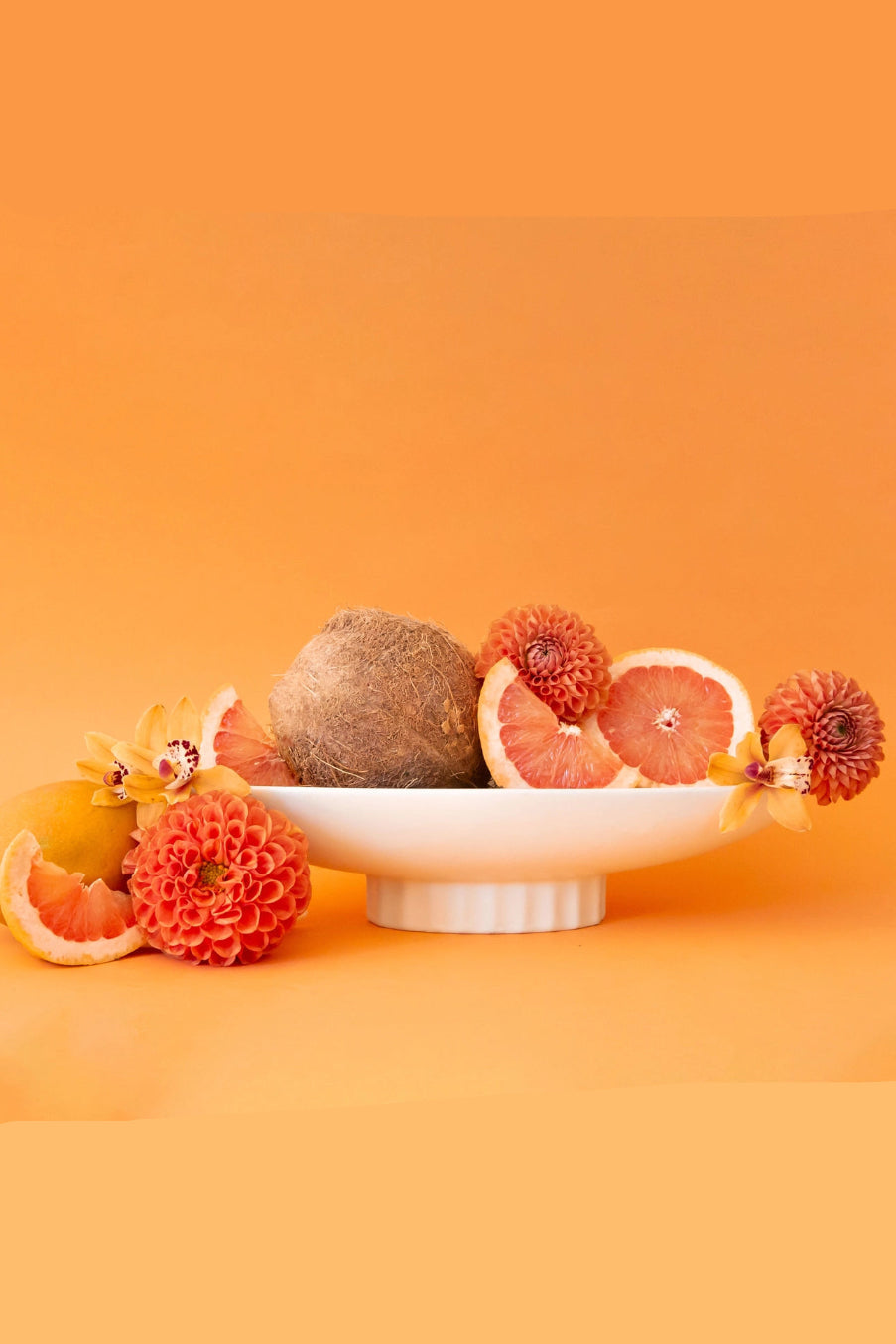 Fruit and flowers on a white Luna Bowl against an orange background ©Jungle Club