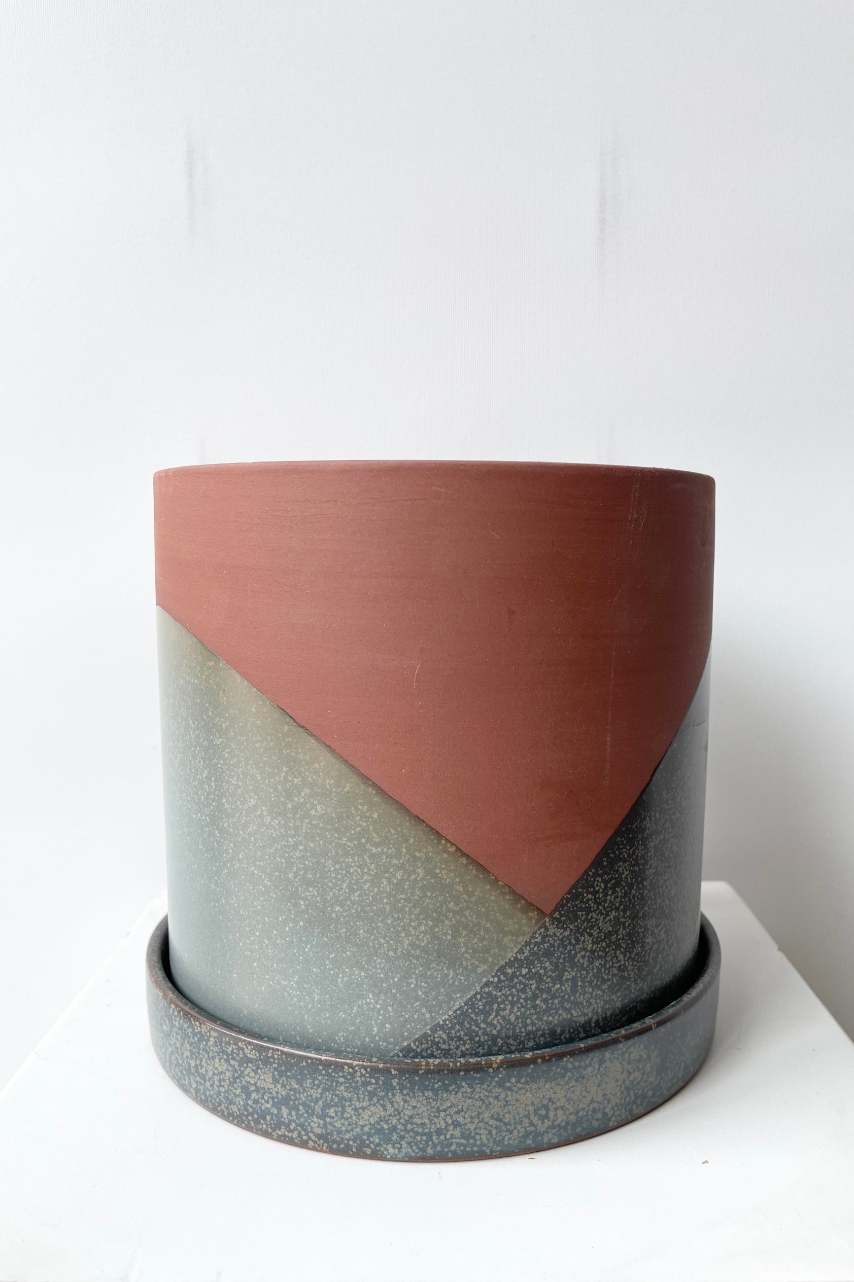 El Cerro pot shown at eye level from the side with its blue and terracotta colors against a white wall.