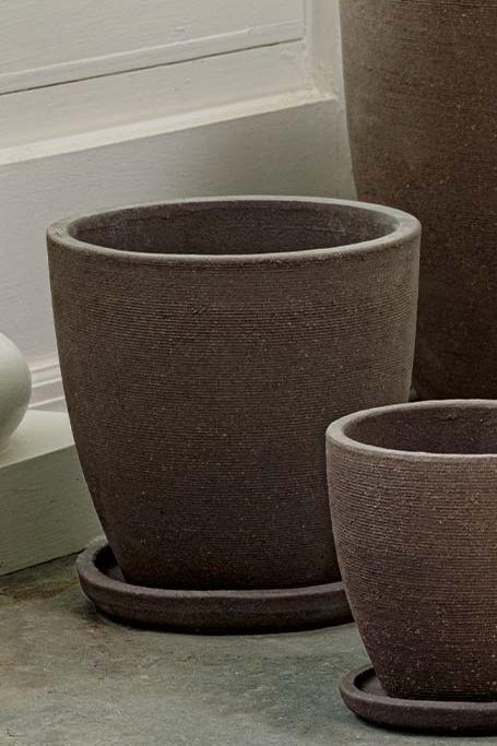 Medium Carob terracotta Lara planter and saucer empty and sitting next to other sizes of empty Lara Carob planters.