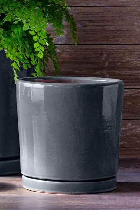 Medium I/O 2 Steel colored ceramic pot and saucer against a wood slab wall.