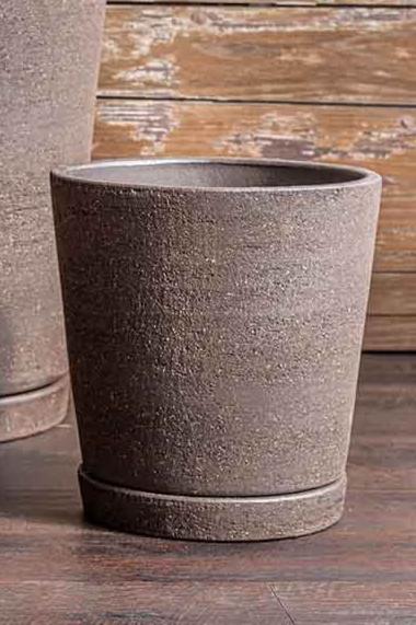 Small I/O Tapered cylinder planter in terra cotta Peat Color empty and against a wood slatted wall.