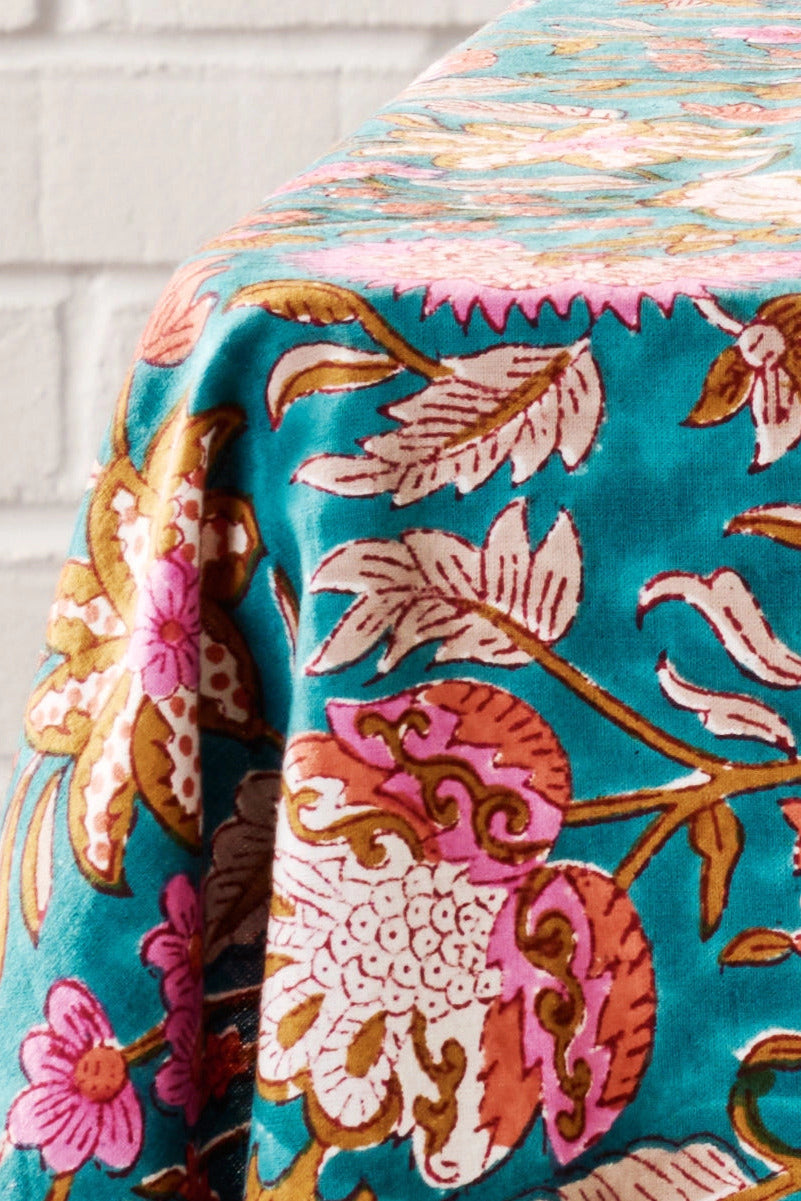 Floral patterned Stabaka Block Print Tablecloth 90 x 60 draped over a surface with a white brick wall background ©Ten Thousand Villages