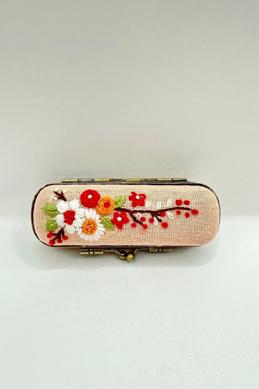 Decorative case with floral embroidery on a light background ©Quince Fables