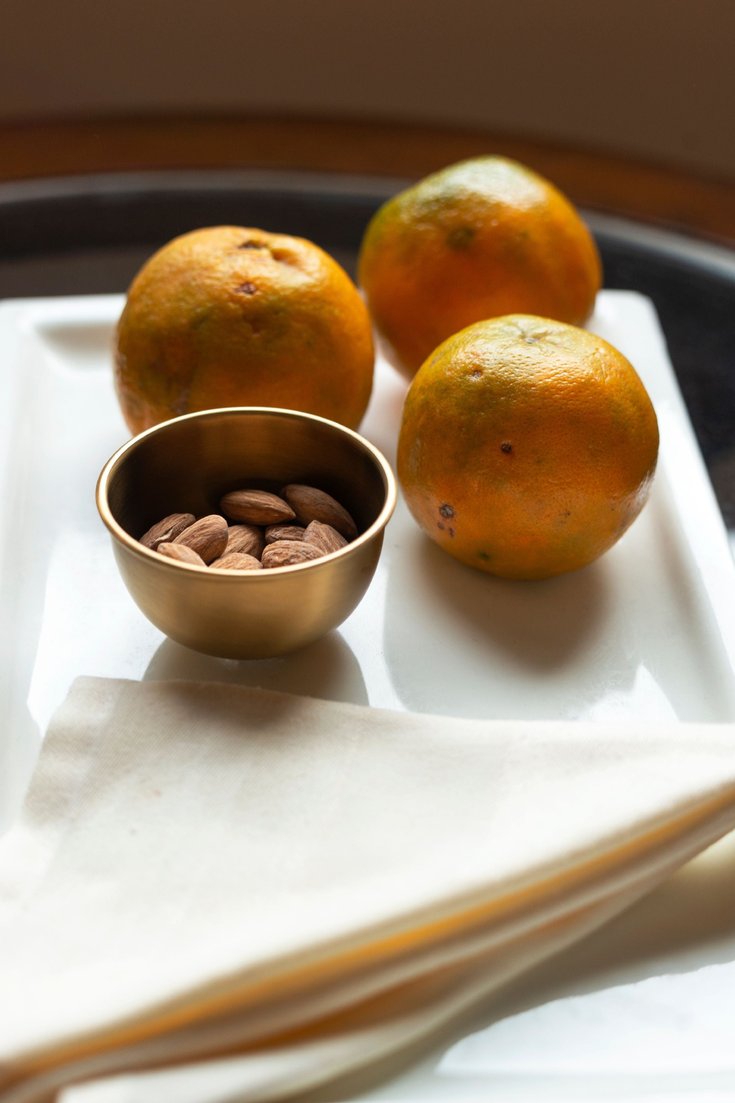Small Brass Bowl by Fog Linen Work with almonds inside and three oranges surrounding it.