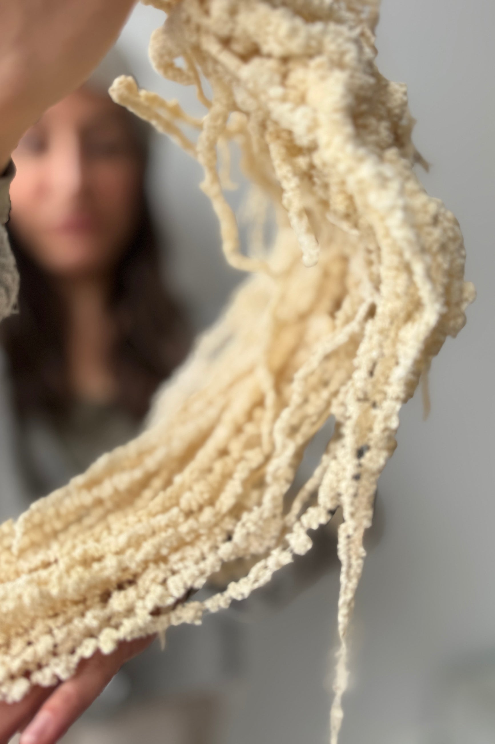 Close-up of a hand holding a bunch of preserved bleached Amaranth with a blurred background ©Sprout Home