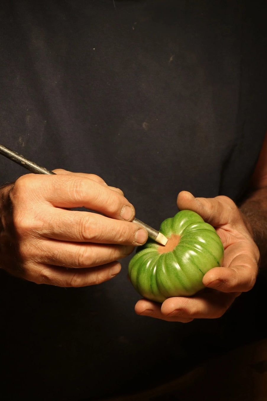 Person carving a beeswax candle with a small knife on a dark background ©Artifaqt