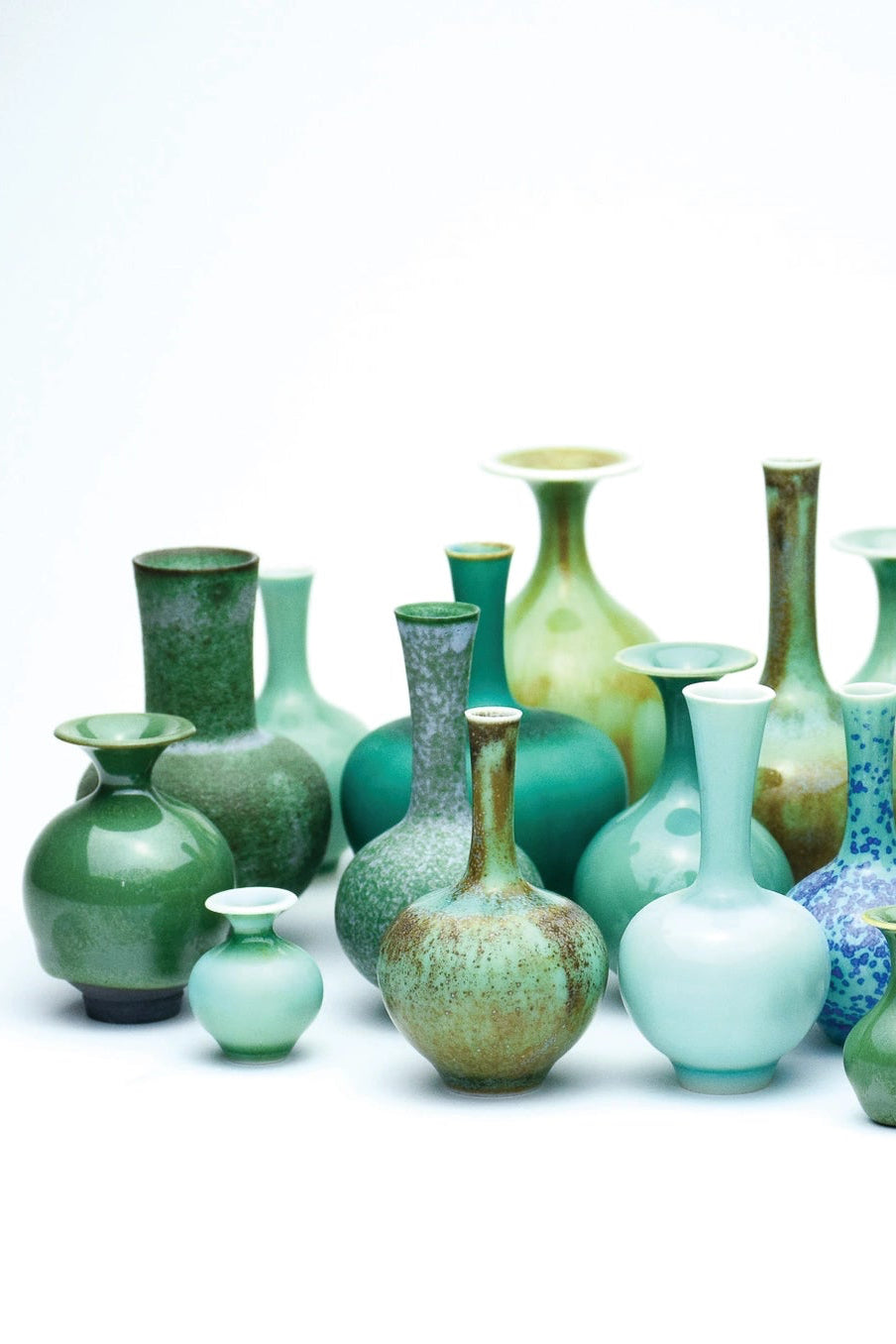 Collection of green ceramic vases with a hand reaching out to touch one. ©SGW Labs