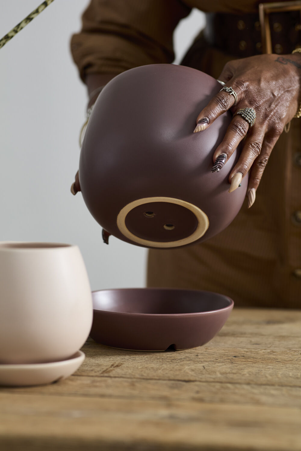 Person holding a Dalton ceramic pot with another pot and bowl on a wooden surface ©Accent Decor