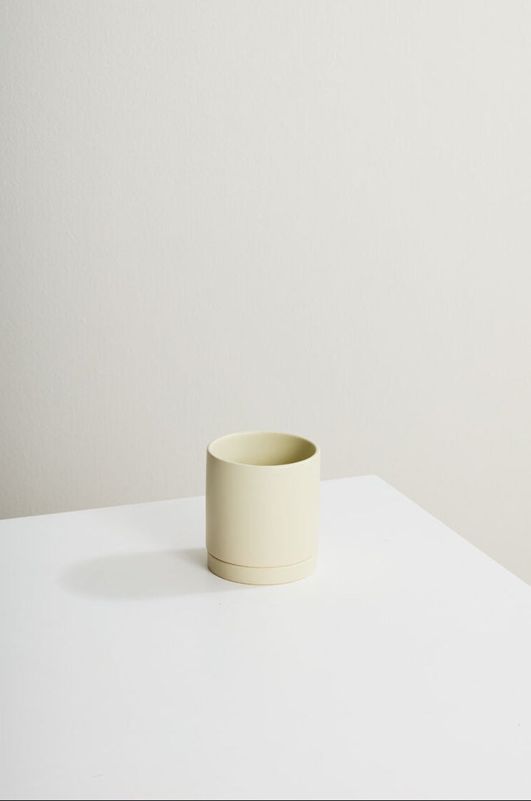 Minimalist scene with a beige ceramic cup on a white surface against a plain wall. ©Accent Decor