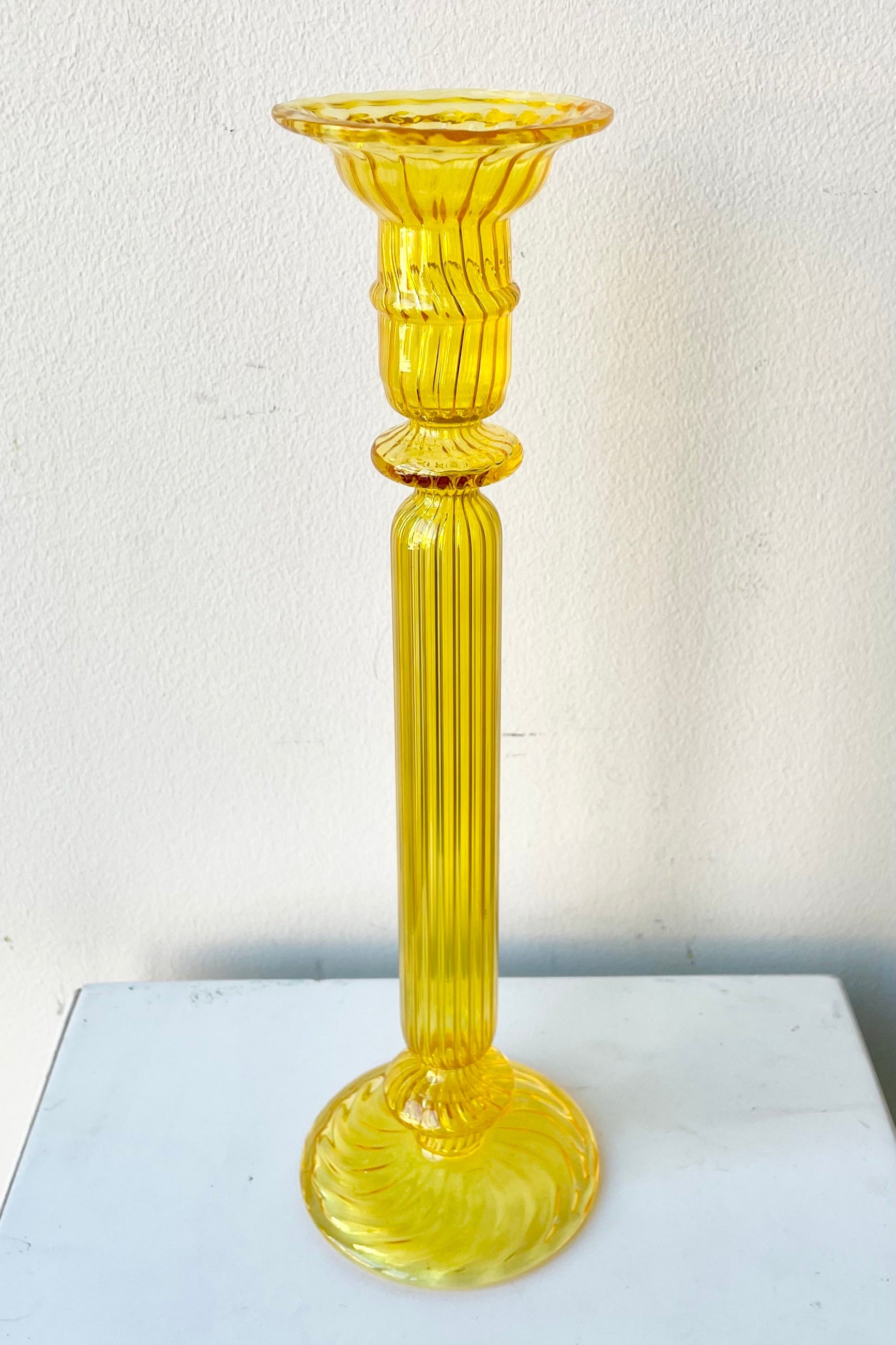 Nalia Daffodil Candlestick holder against. white wall. ©Sprout Home