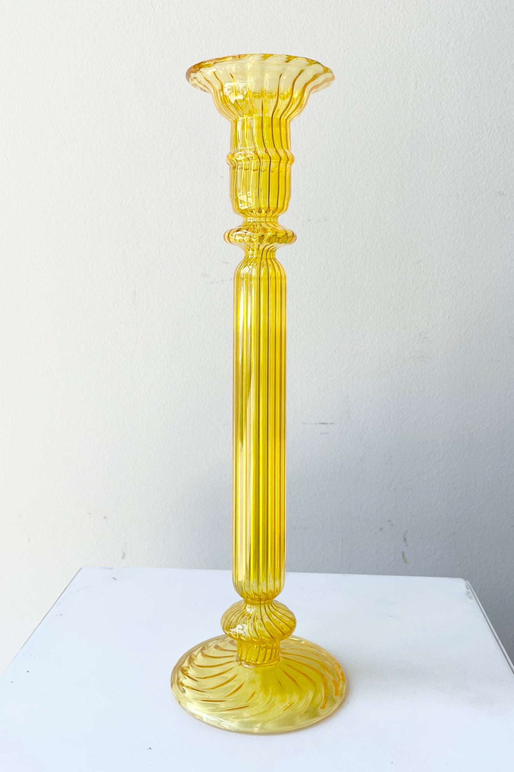 Nalia Daffodil Candlestick holder against. white wall. ©Sprout Home