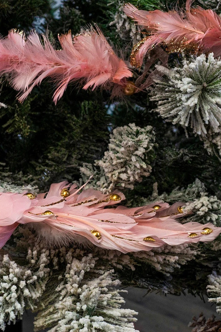 A decorative pink bird ornament with gold accents on a flocked tree ©Zucker Feather Products
