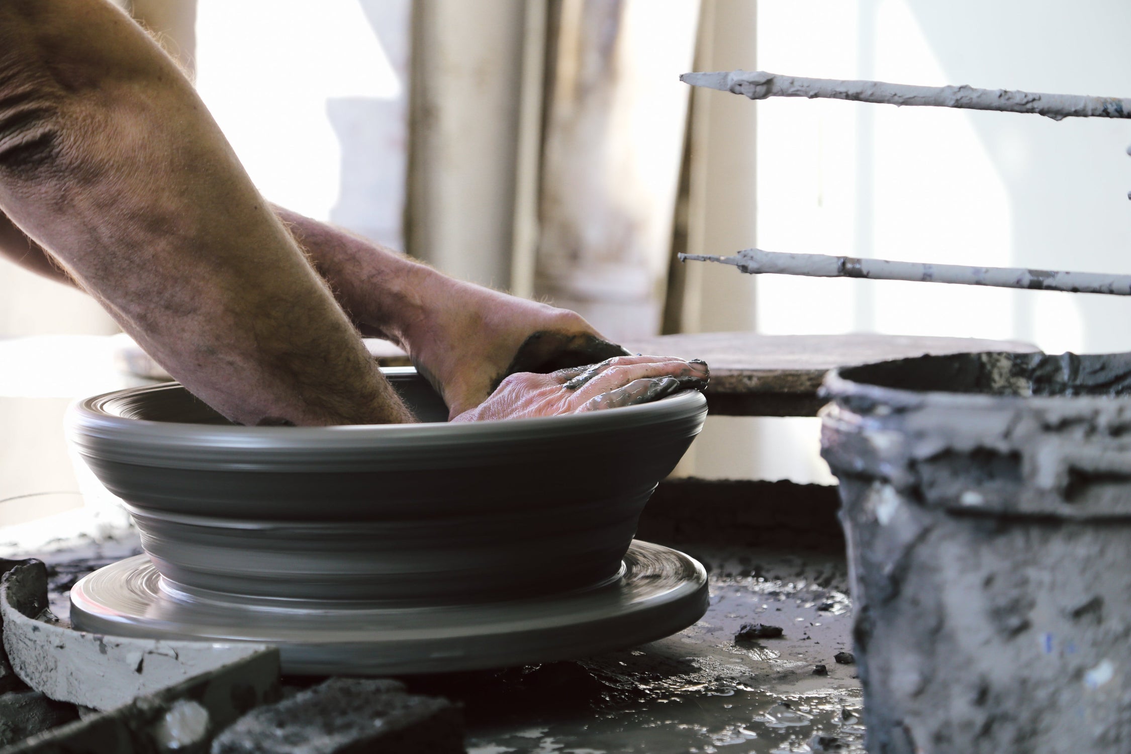 Person working with clay on a pottery wheel in a studio setting. ©Bergs Potter