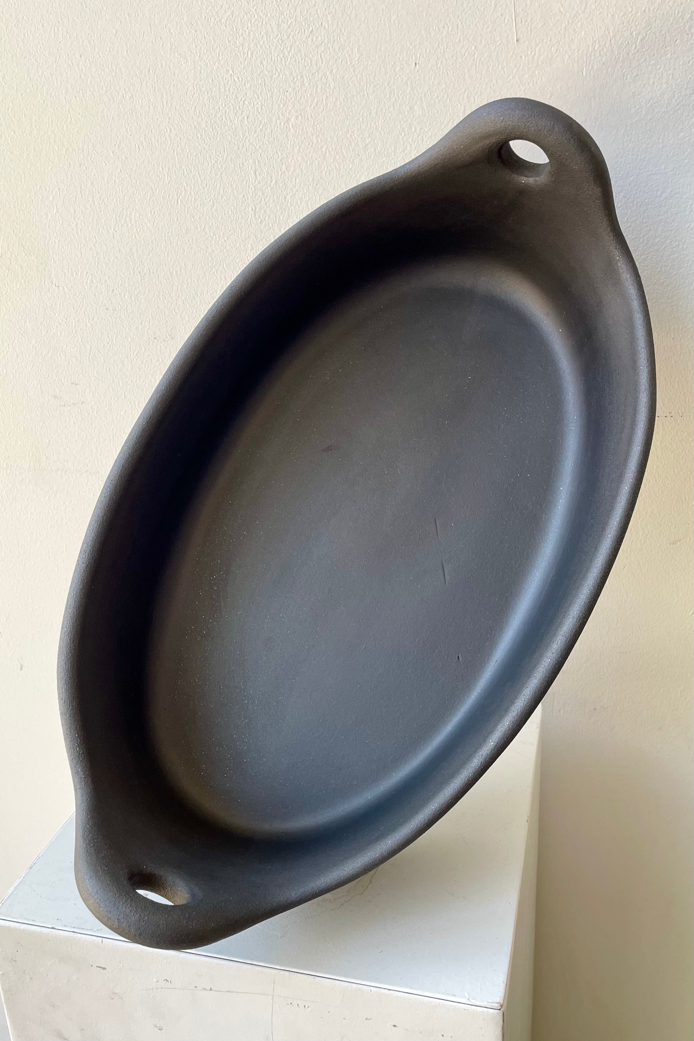 The large Barro Oval Roaster sitting on its side against a white wall.