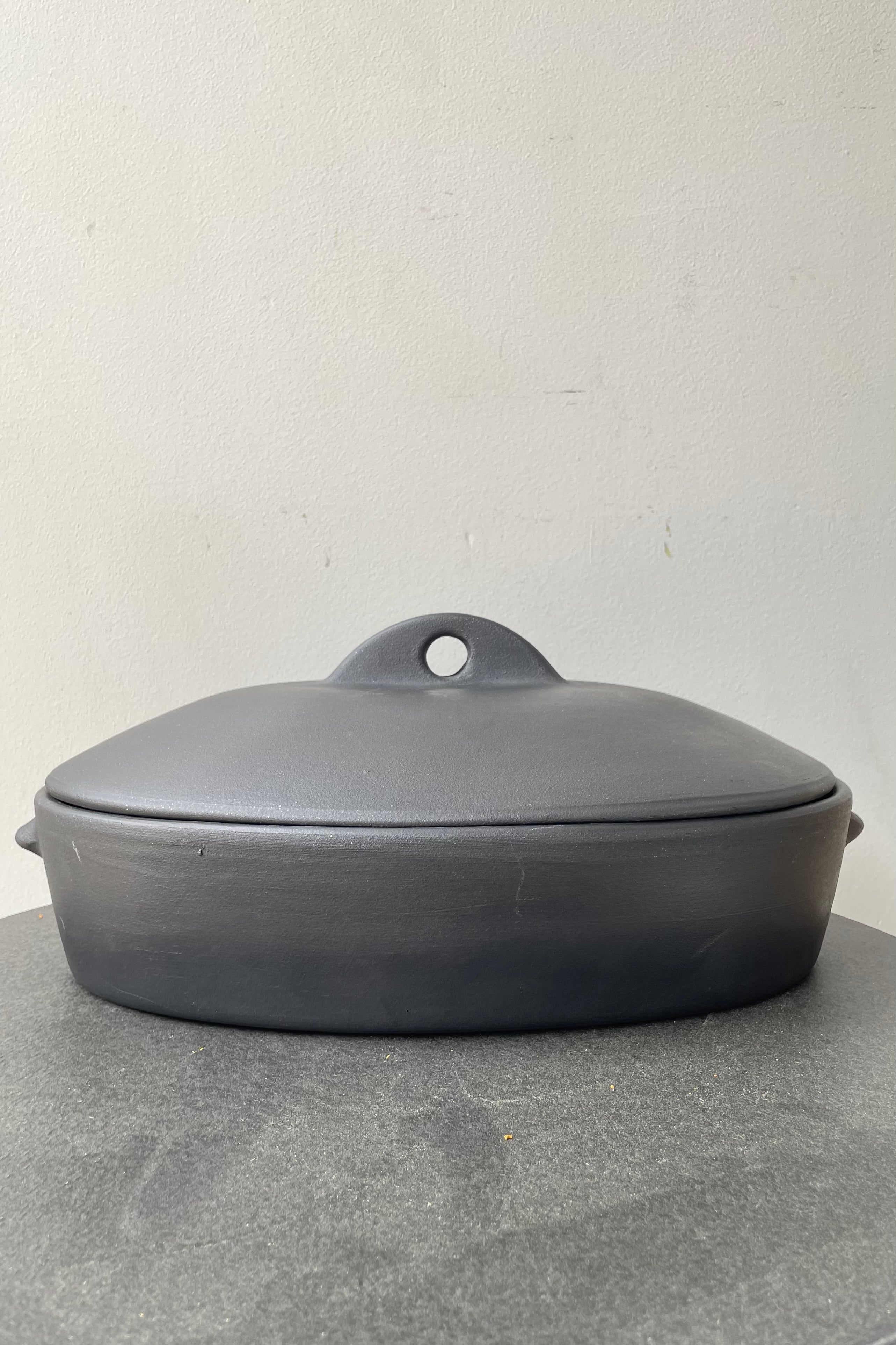 The Barro Lidded roaster pictured from the side against a white wall.
