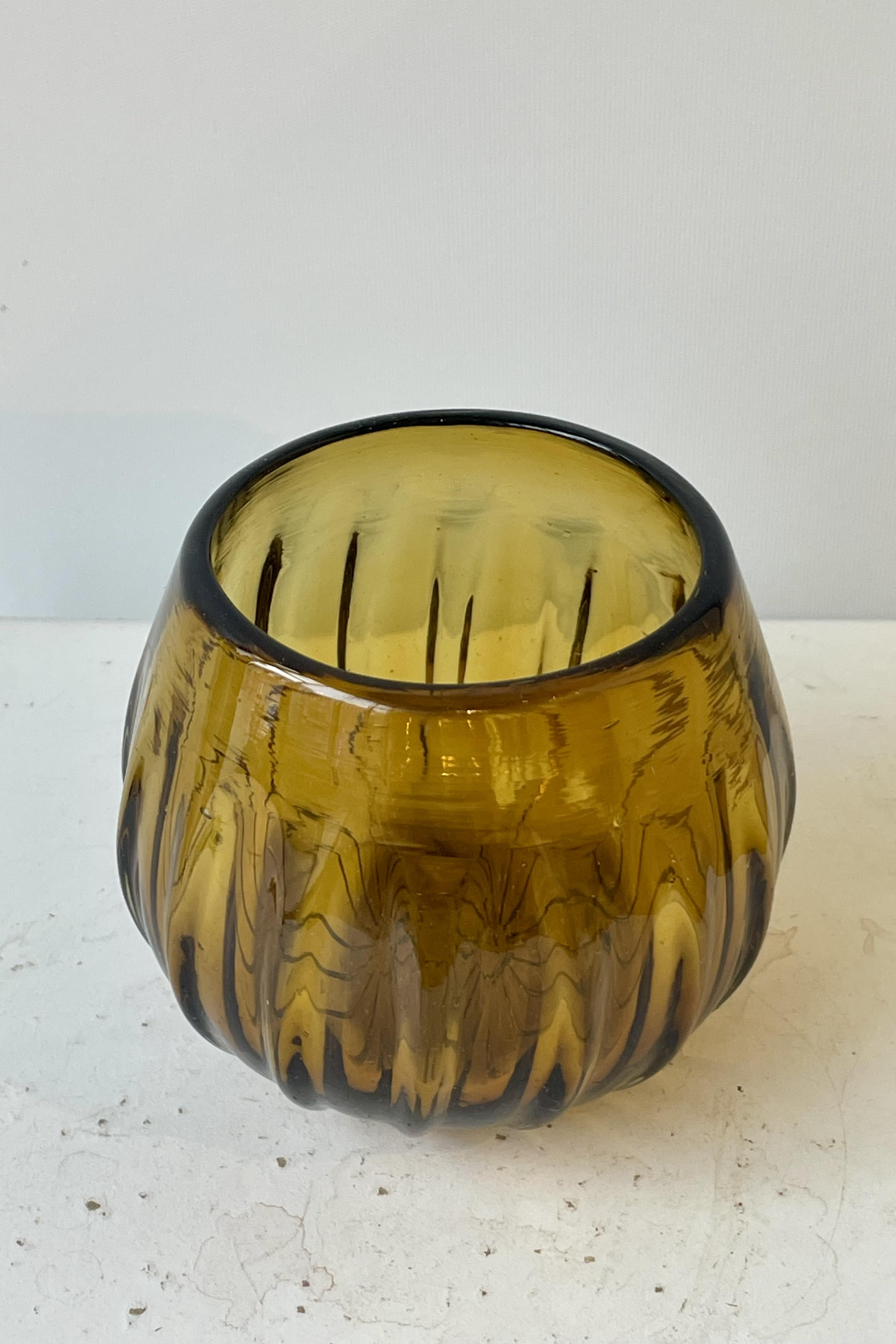 Stemless amber colored wine glass on a white surface in a white room