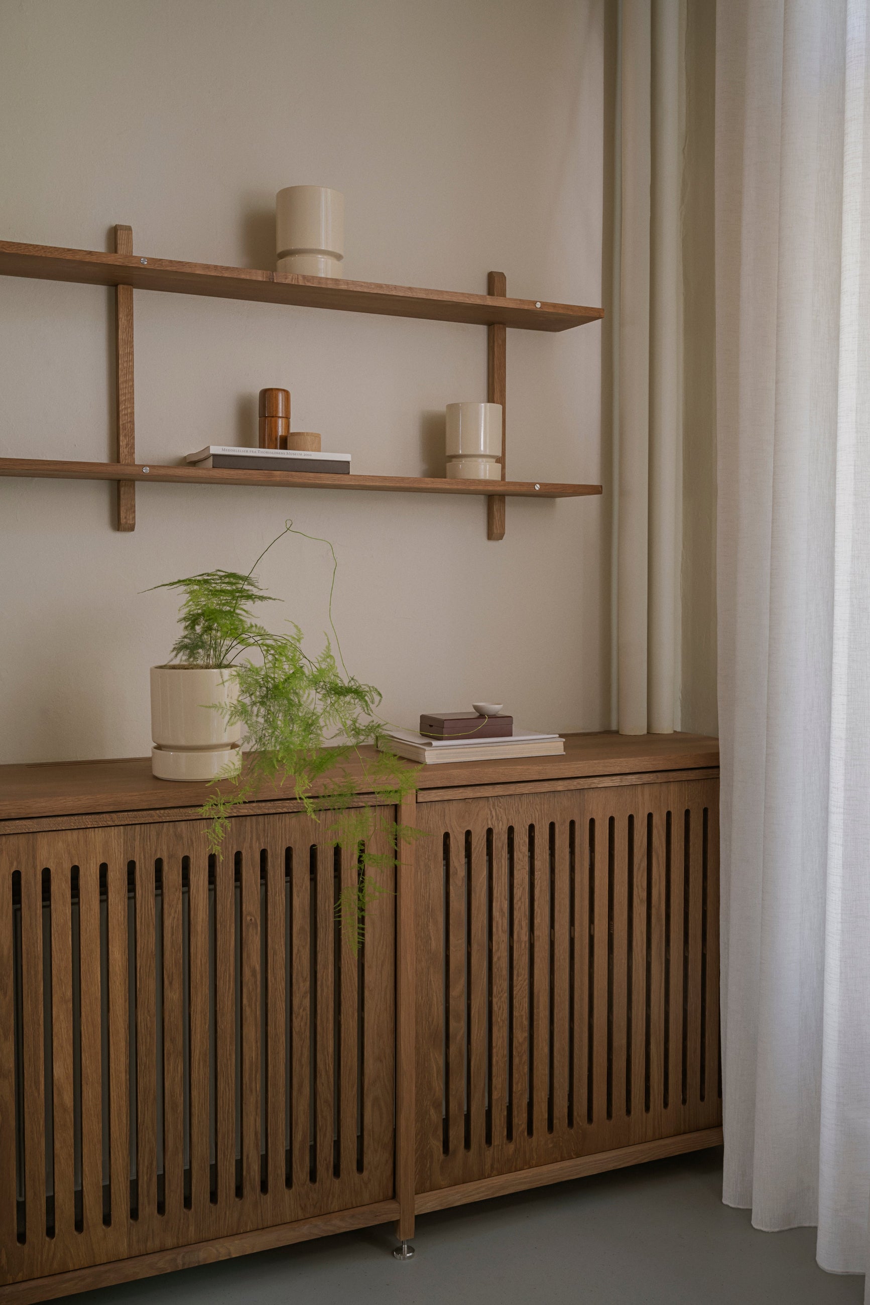 Wooden shelf with sandstone Hoff Pots and decorative items against a neutral wall. ©Bergs Potter