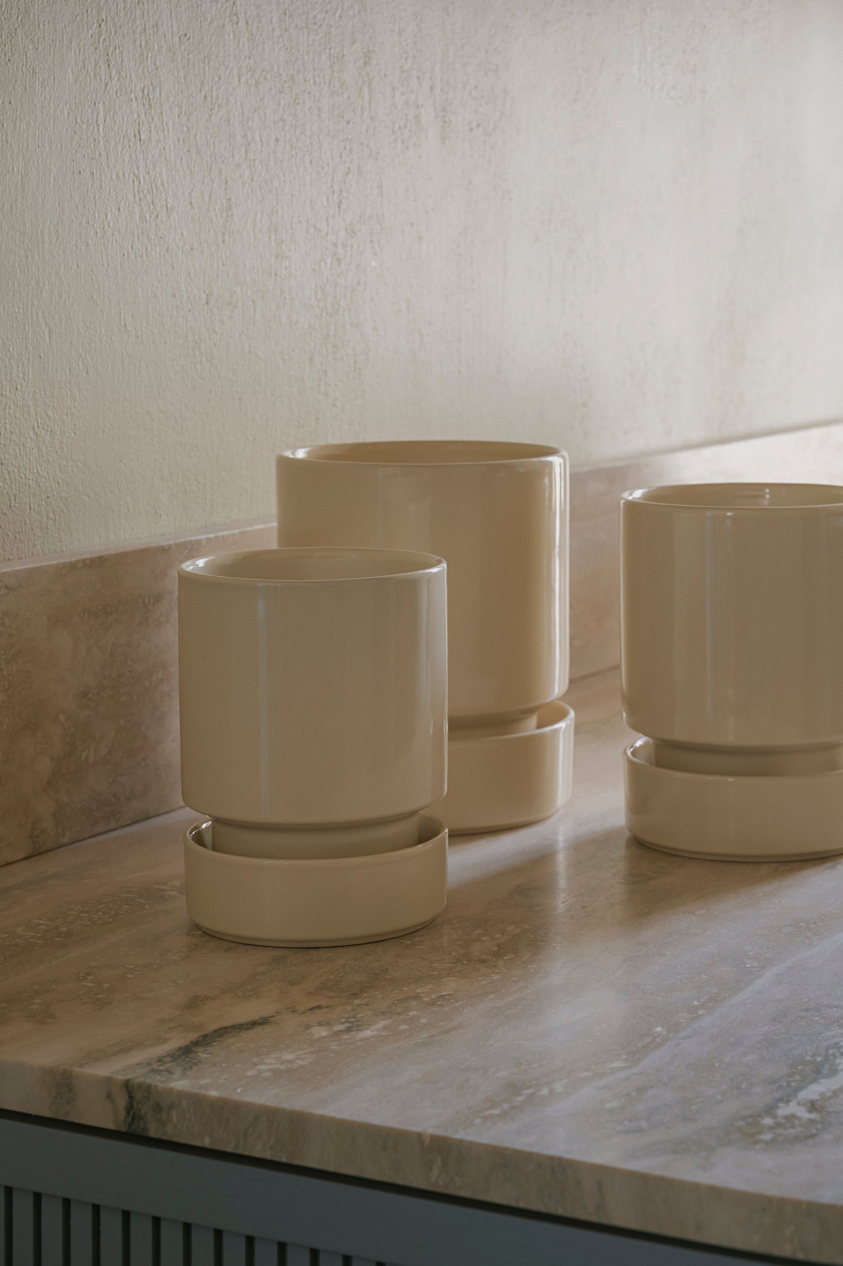 Three Sanstone Hoff ceramic planters on a marble surface with a neutral wall background ©Bergs Potter
