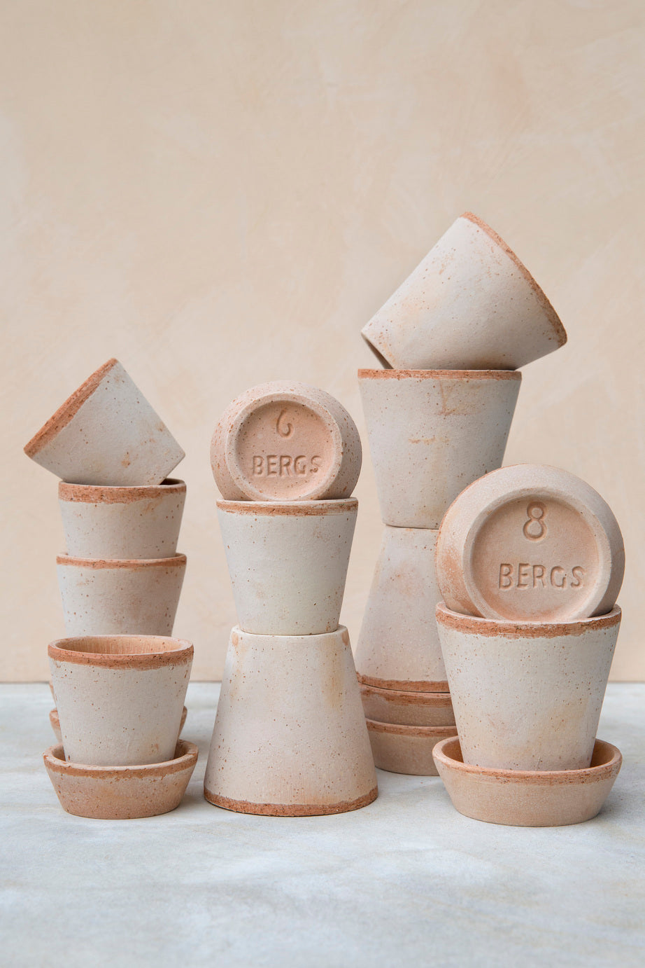Various sized Rosa Julie pots and saucers by Bergs Potter against a peach backdrop. ©Bergs Potter