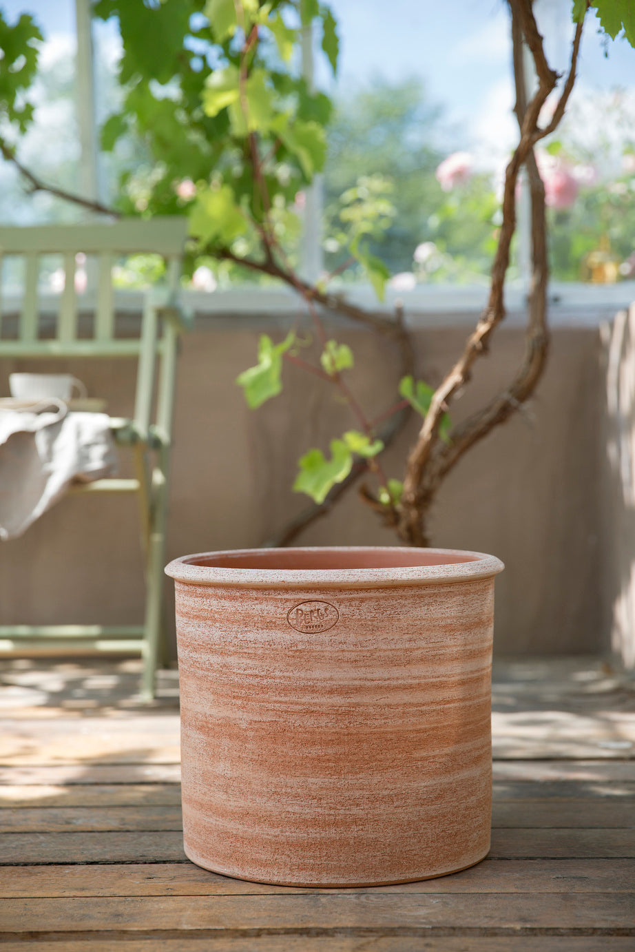 Terracotta Rosa Modena pot on a wooden deck with a blurred garden background ©Bergs Potter