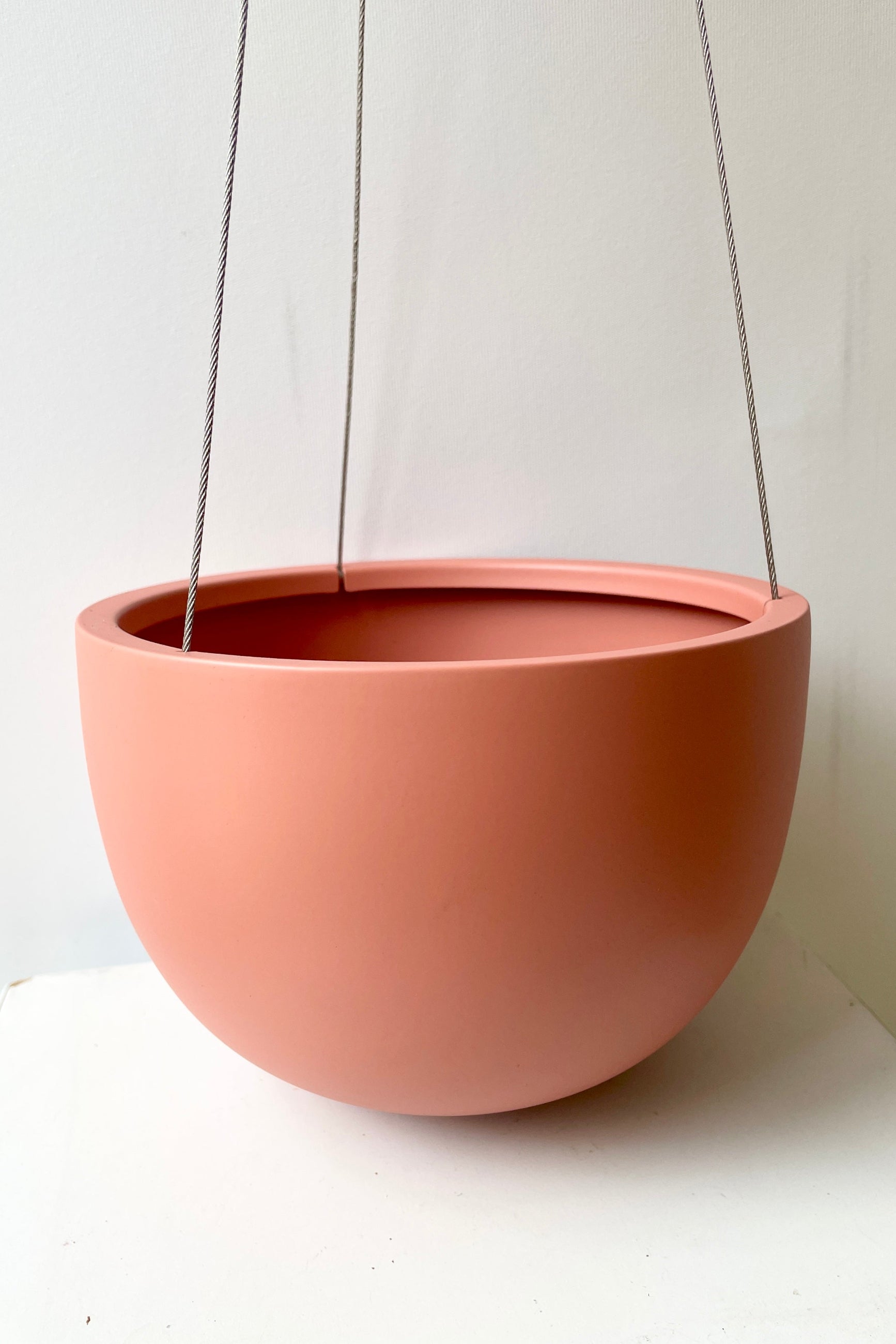 An empty Clifton matte dusty pink hanging pot against a white wall ©Sprout Home
