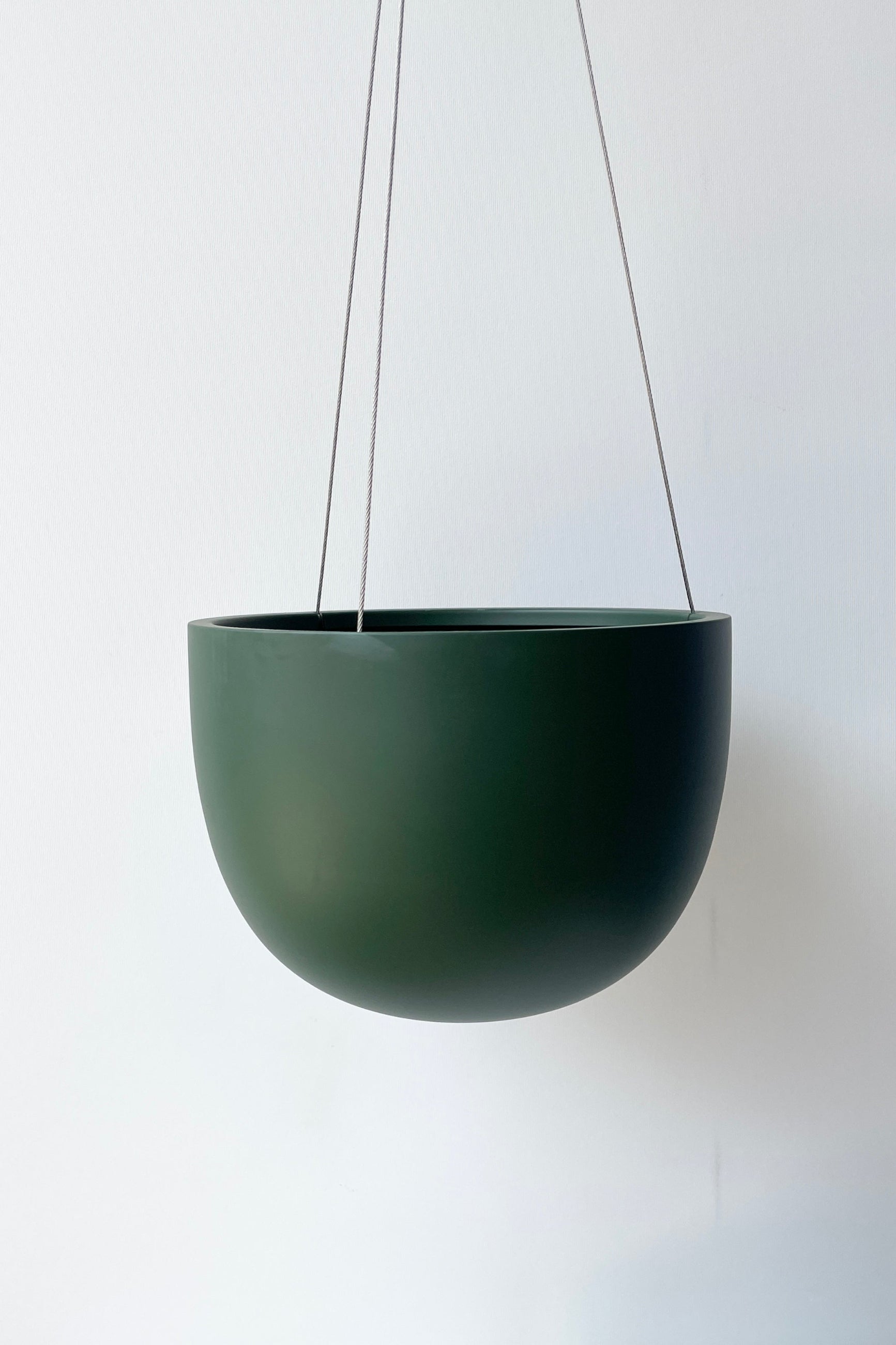 Clifton Matte Forest Green hanging pot empty against a white wall ©Sprout Home