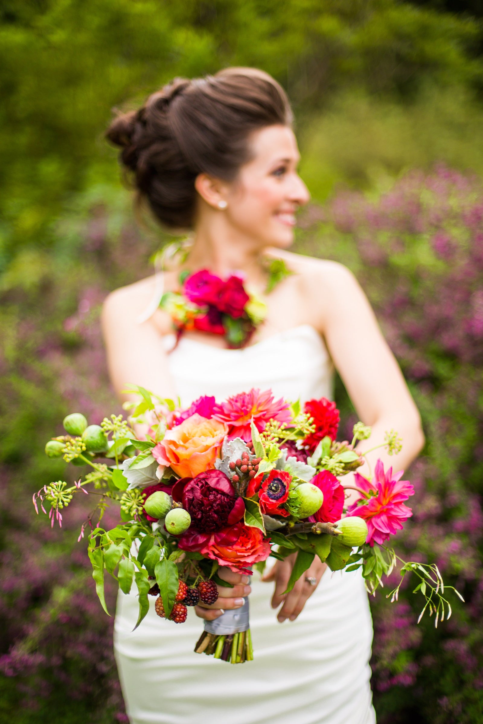 Cody & Joe's wedding with the bride holding a bright and fun red and green floral bouquet and wearing a floral necklace. Floral by Sprout Home. Photograph by Ava Weddings Fine Art Photography