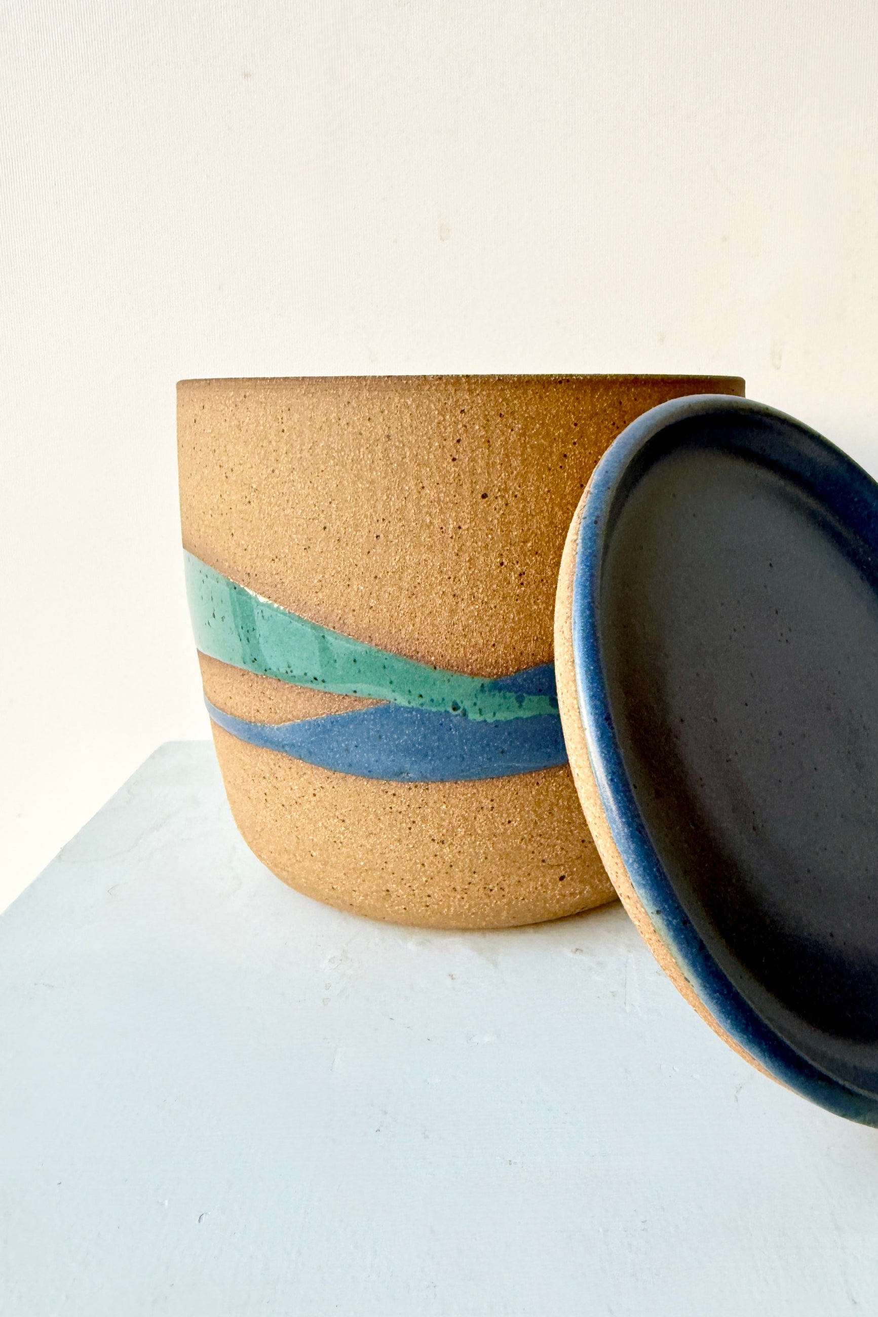 Cylinder Pot & Saucer Denim and Dark Teal Splash Glaze 4.5" with its saucer leaning against the pot handmade by Christina Kosinski on a white background ©Sprout Home