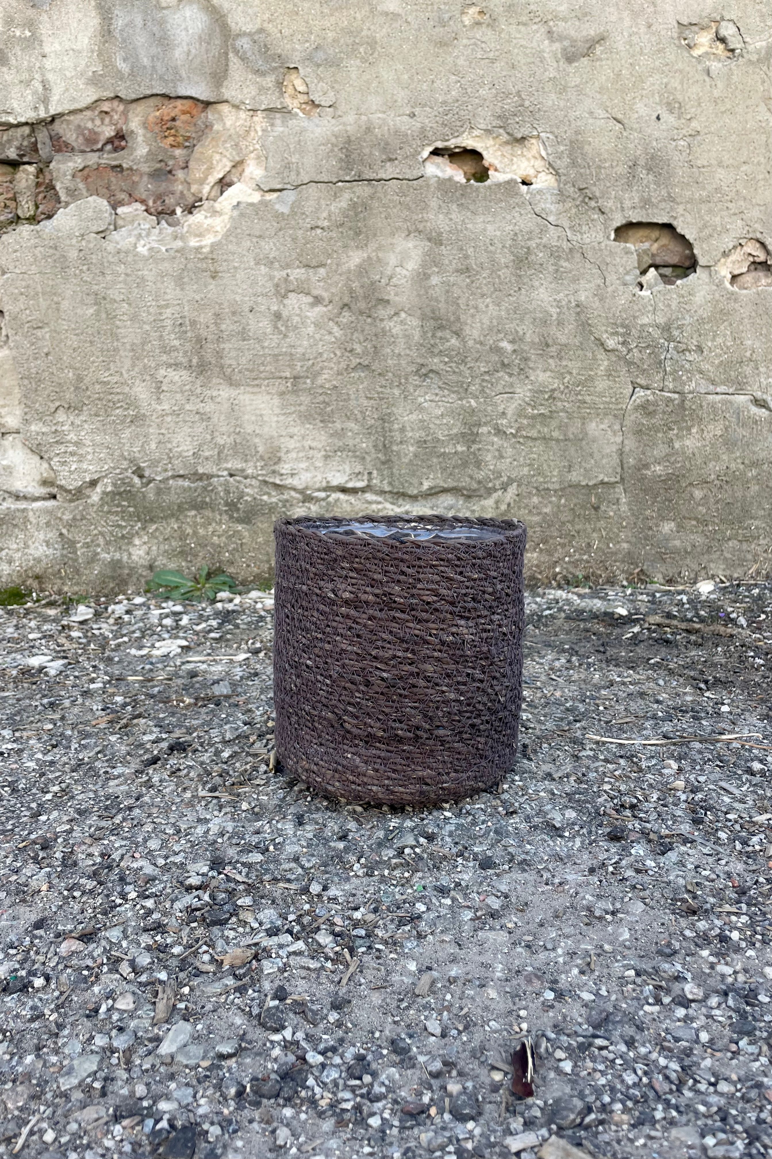 Photo of black seagrass basket with liner against a cement wall.